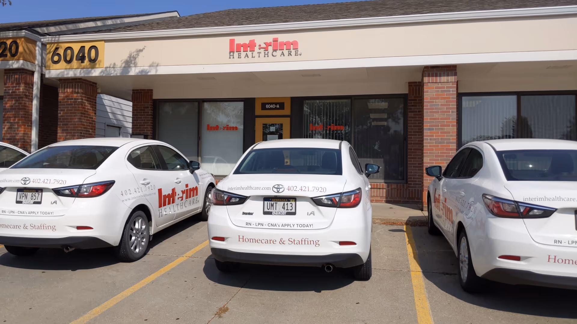 Exterior view of Interim HealthCare of Lincoln with three white company cars parked in front.