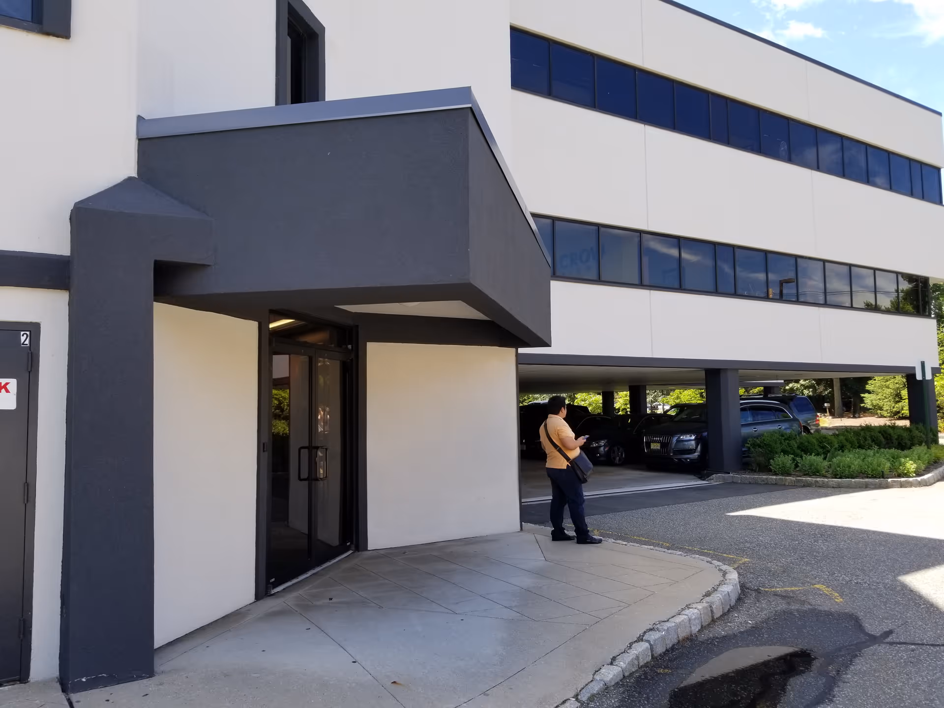 Exterior view of a modern senior care facility with a covered entrance and parked cars.