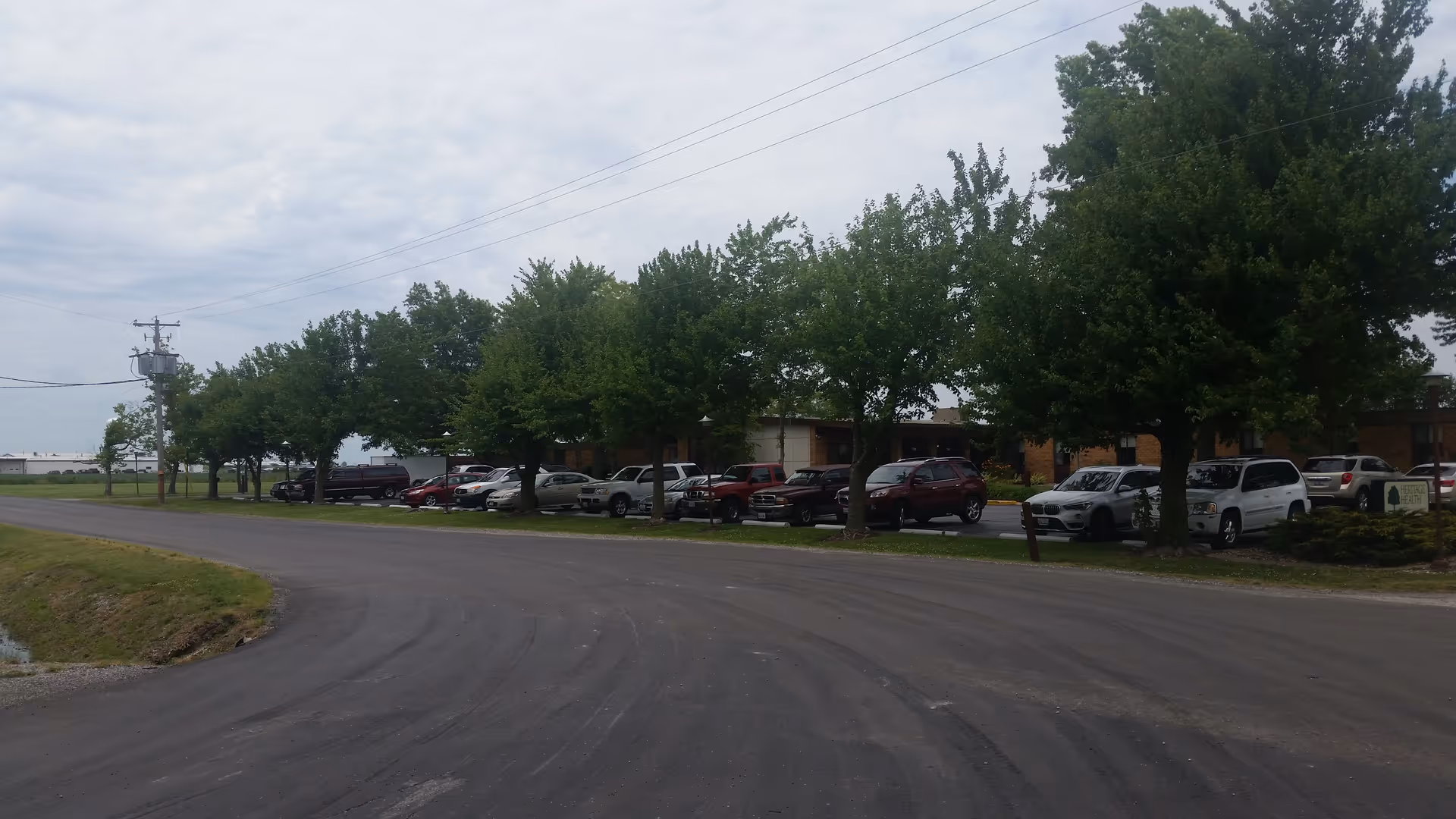 Exterior view of Lakeside Health and Rehab Center, showing a curved road and parked cars.