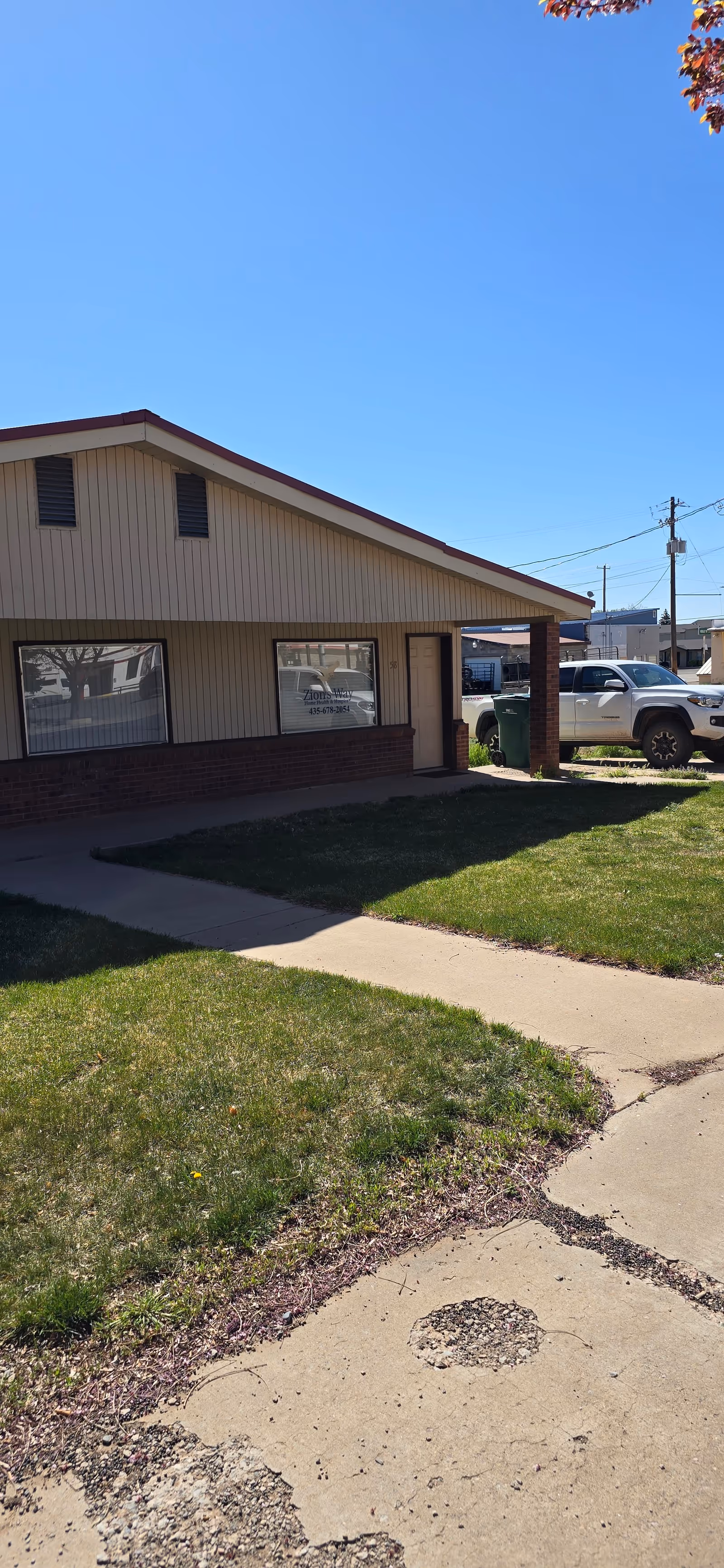 Exterior view of Zion's Way Home Health & Hospice building with sidewalk and parked cars.