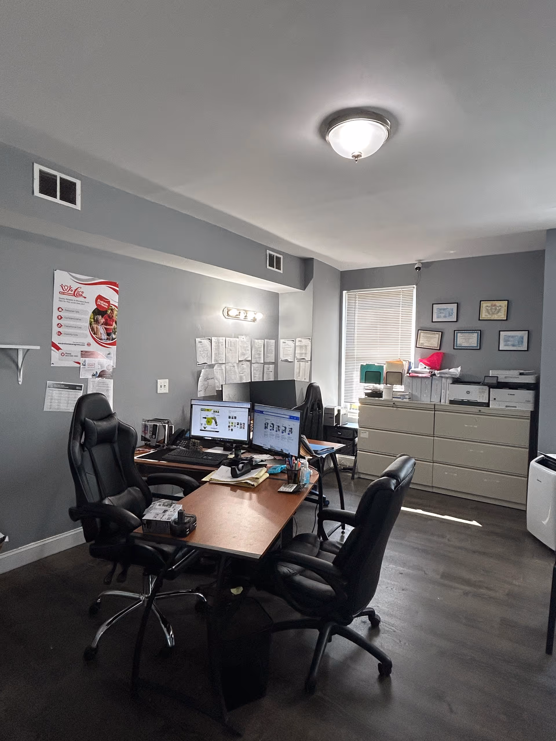 Office workspace with desks, chairs, computers, and filing cabinets in a senior care facility.