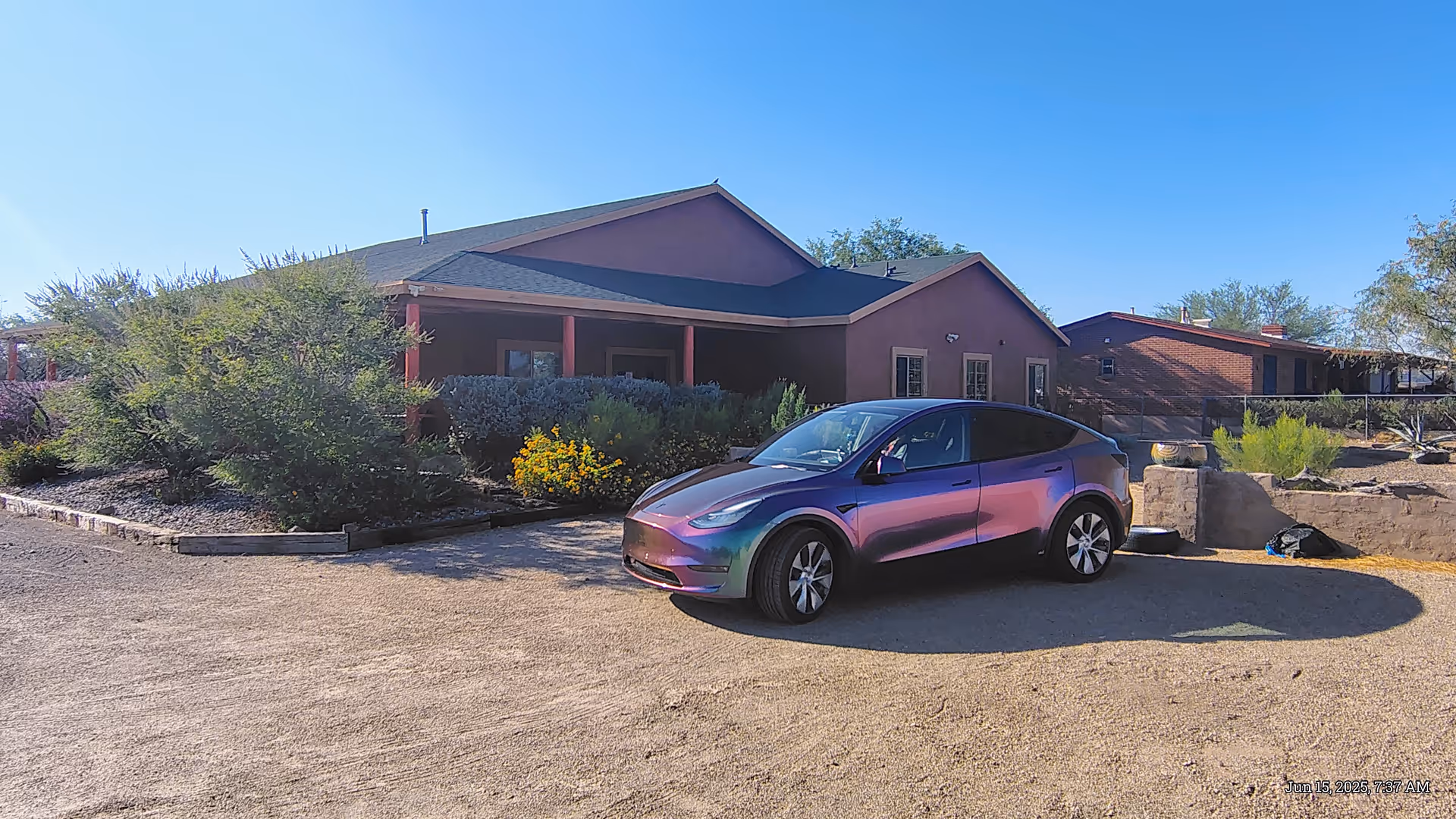 Rainbow-colored Tesla parked in front of a single-story Rancho Verde Los Reales building.