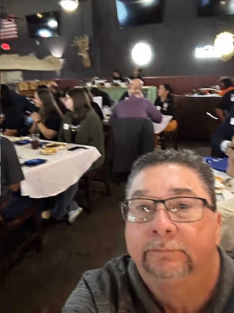 Selfie of a man in a busy dining room with residents seated at tables.