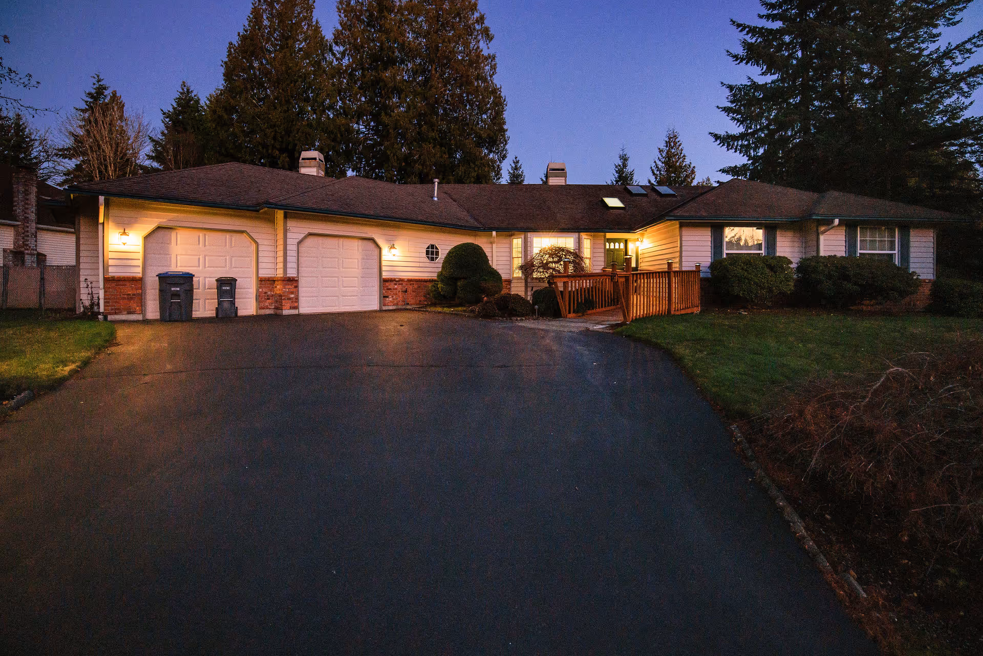 Exterior view of a single-story senior living facility with a driveway and lit entrance.