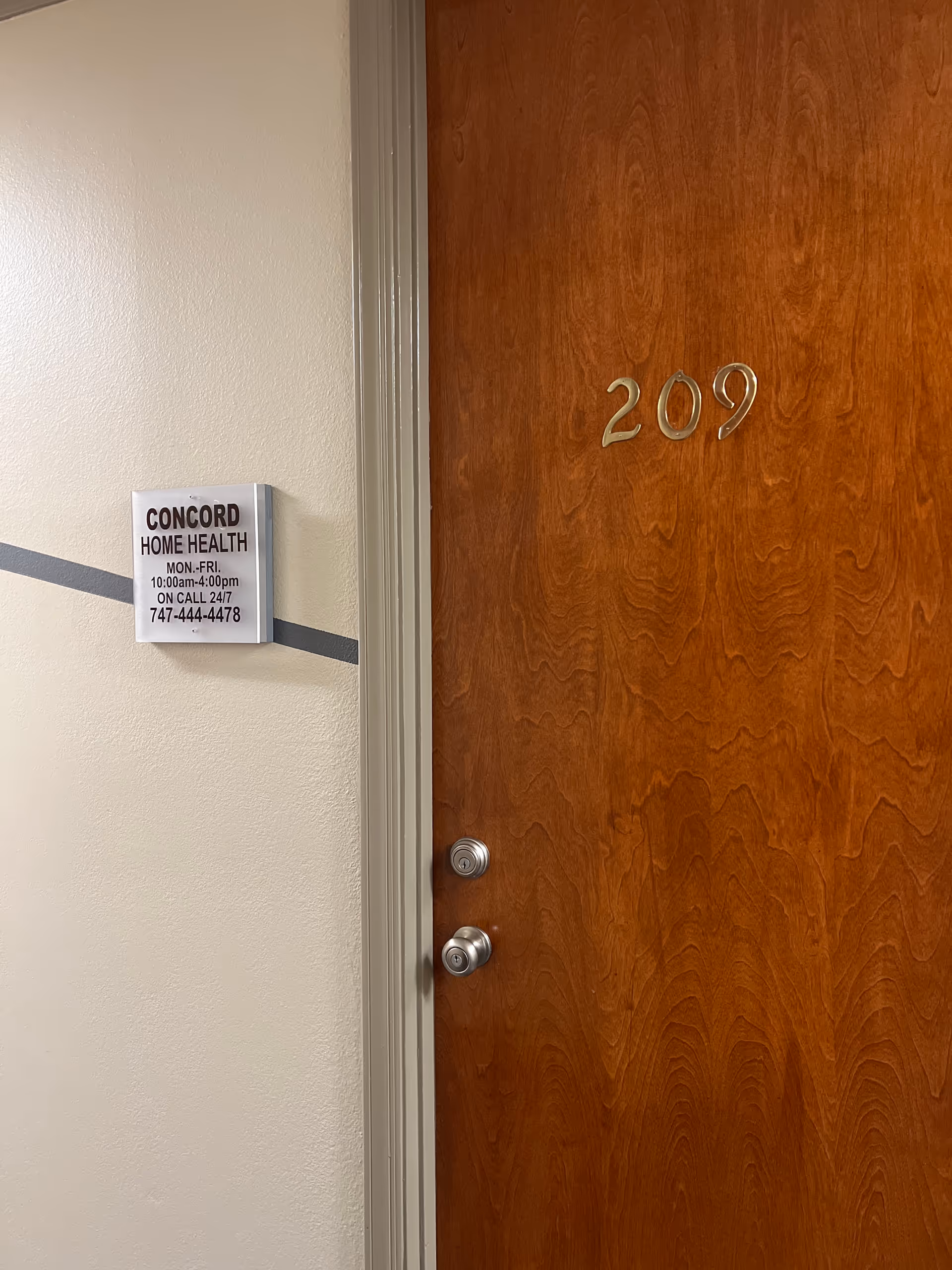 Wooden door numbered 209 next to Concord Home Health sign in a hallway.