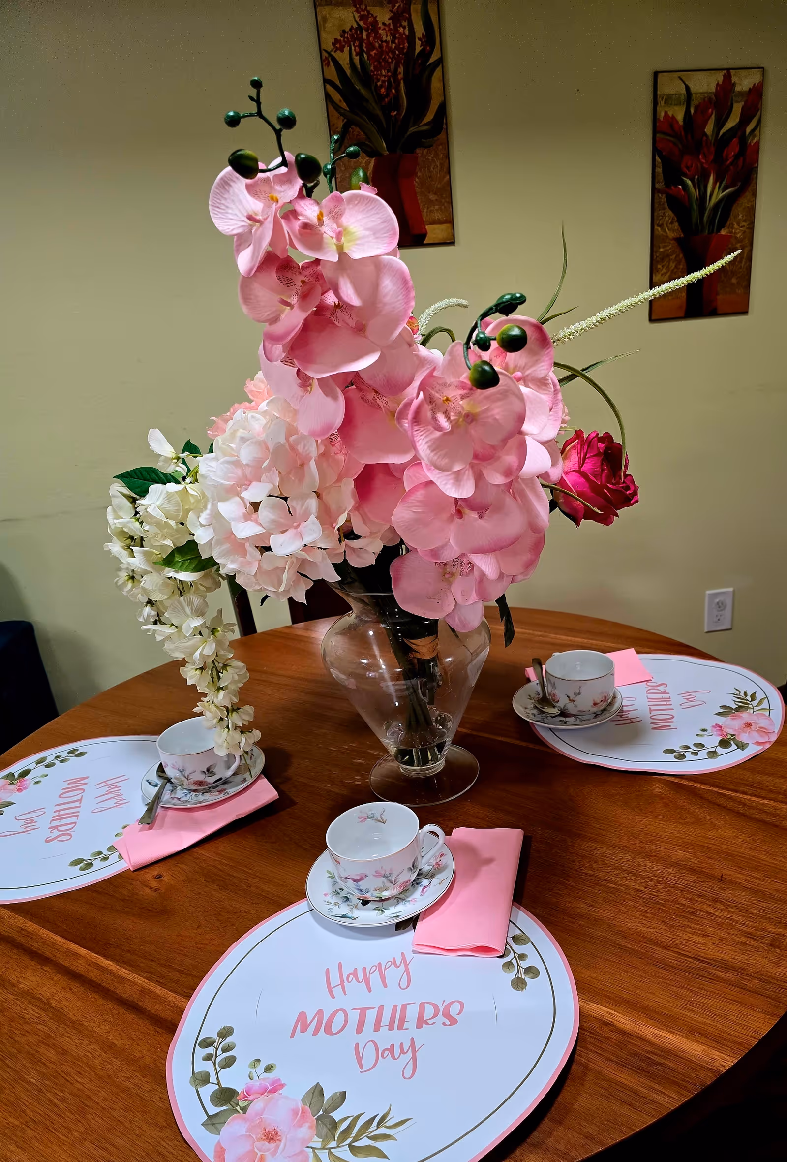 Round dining table with pink flower centerpiece and Mother's Day place settings.