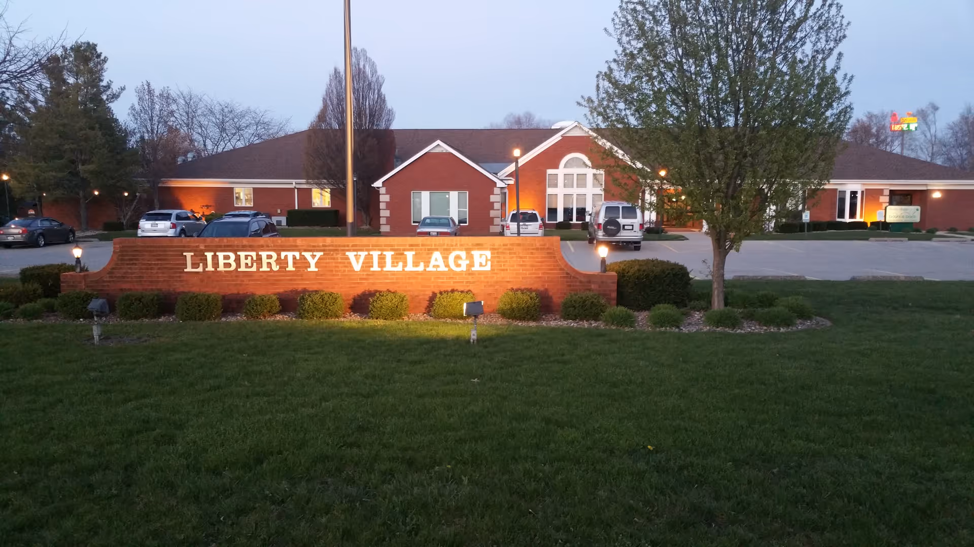 Exterior view of a brick building with a Liberty Village sign and parked cars.