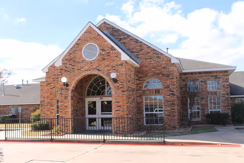 Exterior of Winnie L Long Term Care Partners, brick entrance with arched doorway and windows.