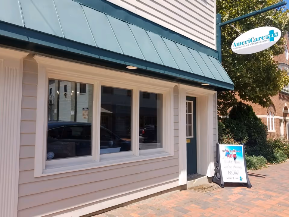 Exterior view of AmeriCare Plus Home Care storefront with sign and hiring board.