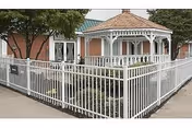 White fence encloses a brick building with a decorative gazebo and porch.