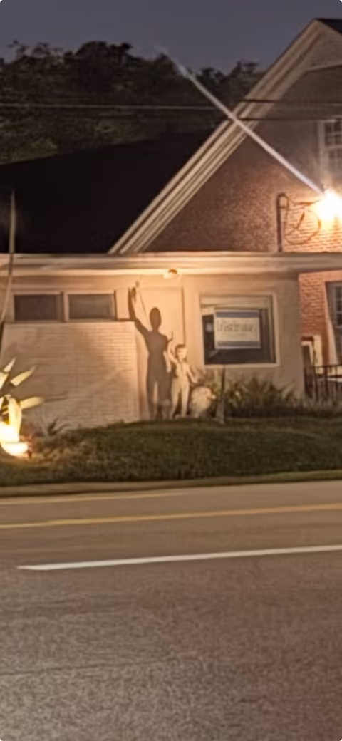 Night view of a brick senior living facility front with illuminated entrance and sidewalk.