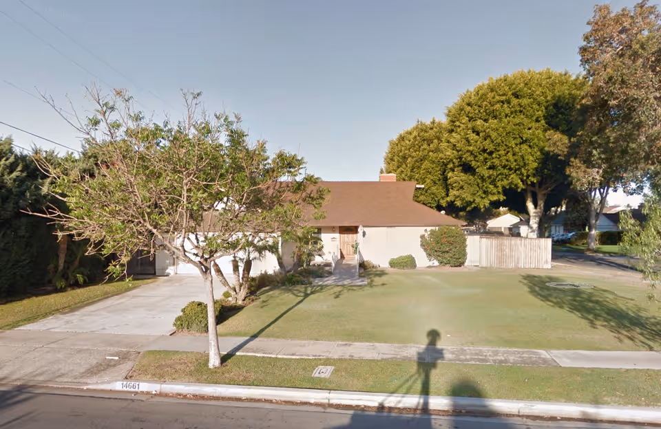 Front exterior of a single-story senior care home with a grassy lawn.