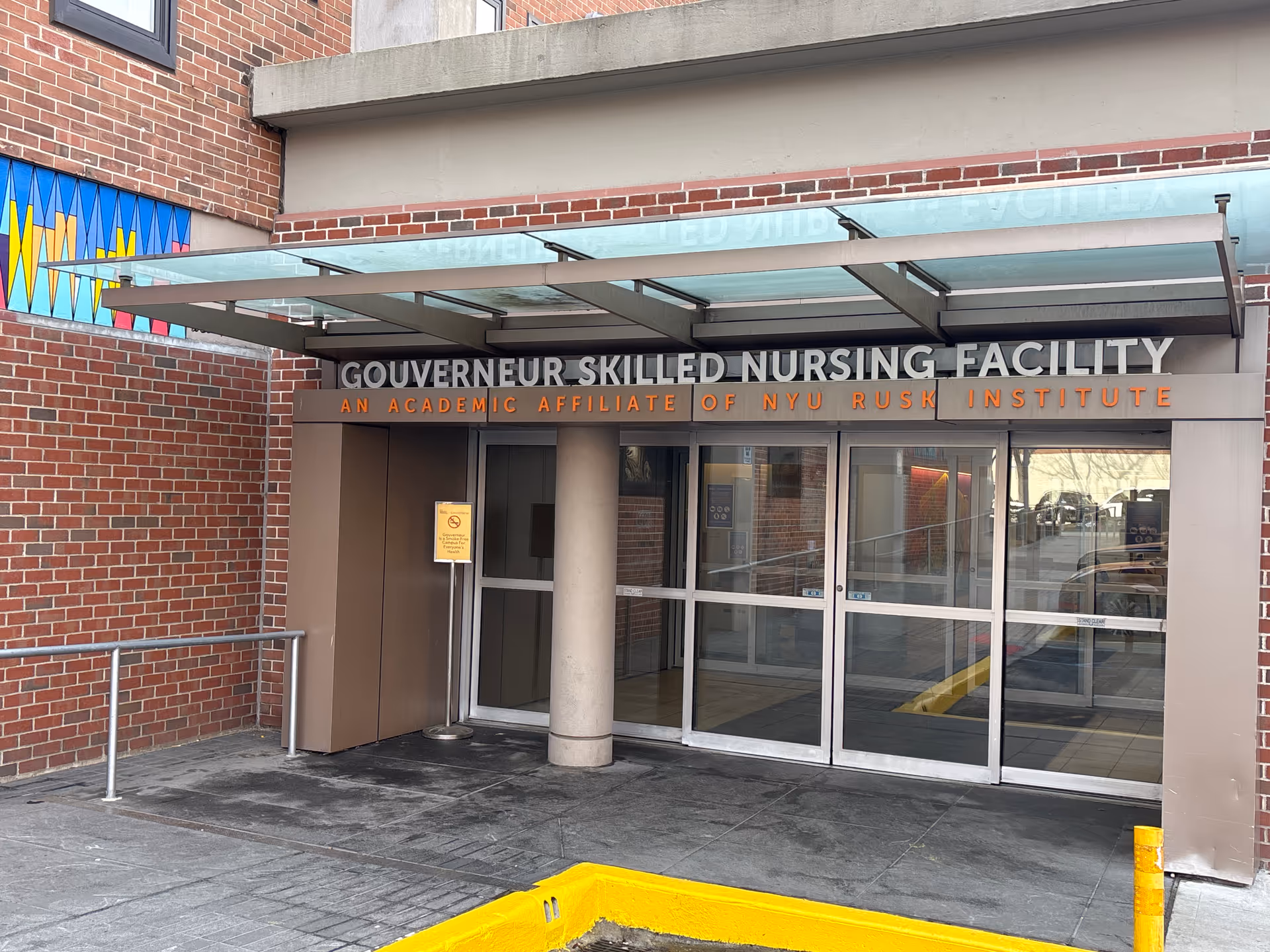 Entrance to Gouverneur Skilled Nursing Facility, brick building with glass doors.