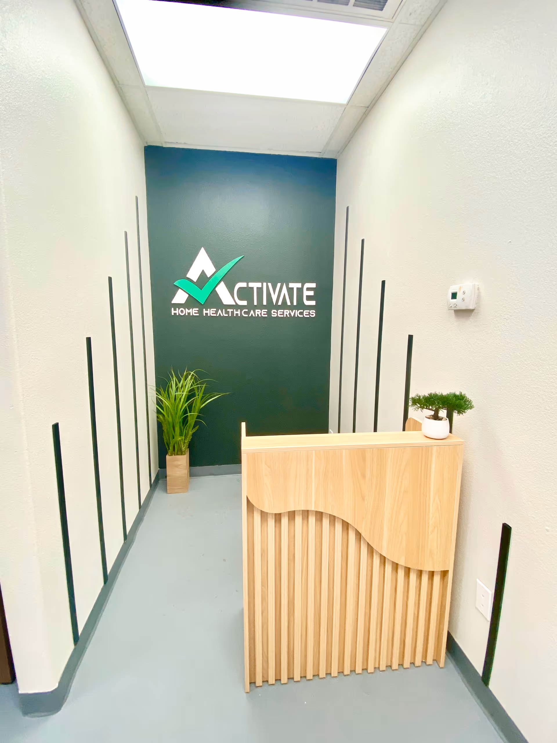 A narrow interior hallway with a reception desk and a green Activate logo wall.