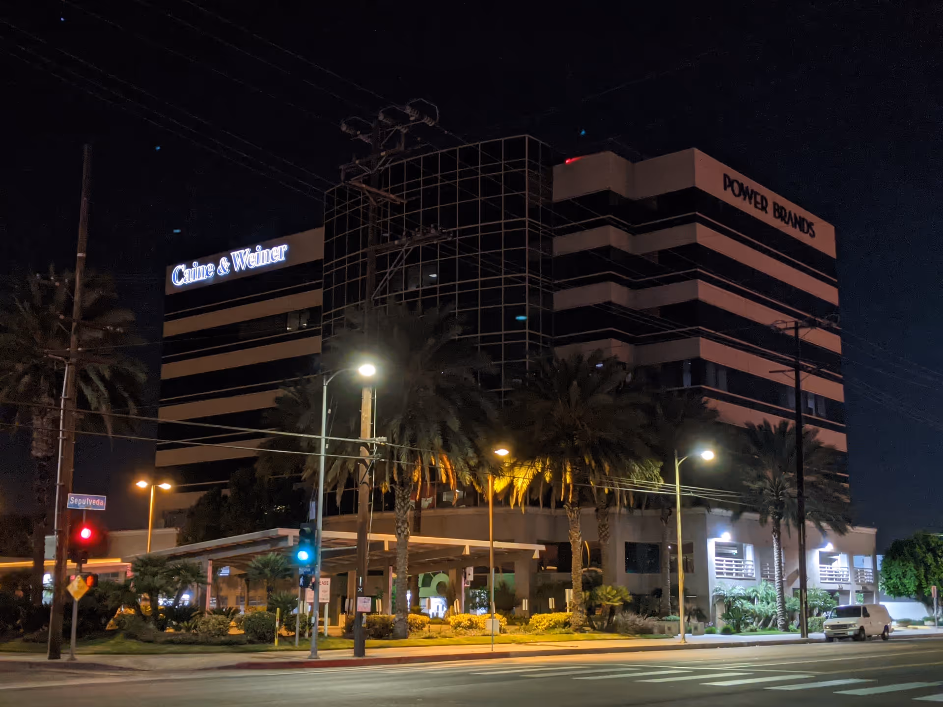 Night exterior of Libertana facility building with palm trees and streetlights.