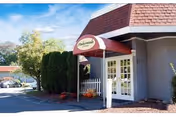 Exterior view of Amberwoods of Farmington entrance with red awning and pumpkins.