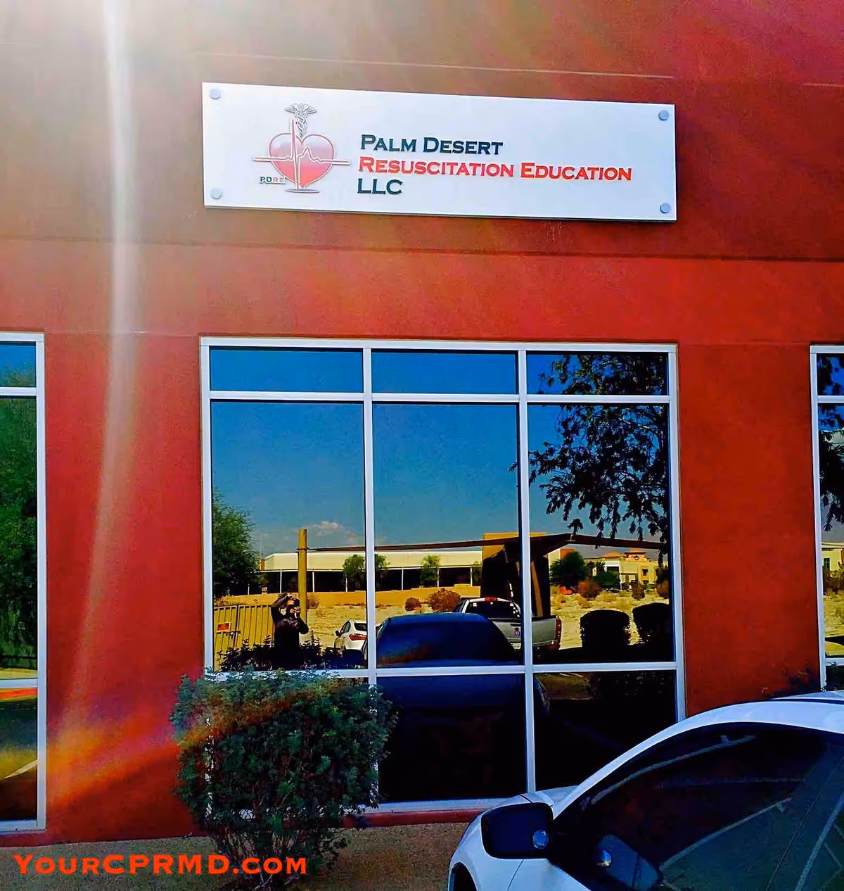 Red building exterior with large glass windows and a Palm Desert Resuscitation Education sign.
