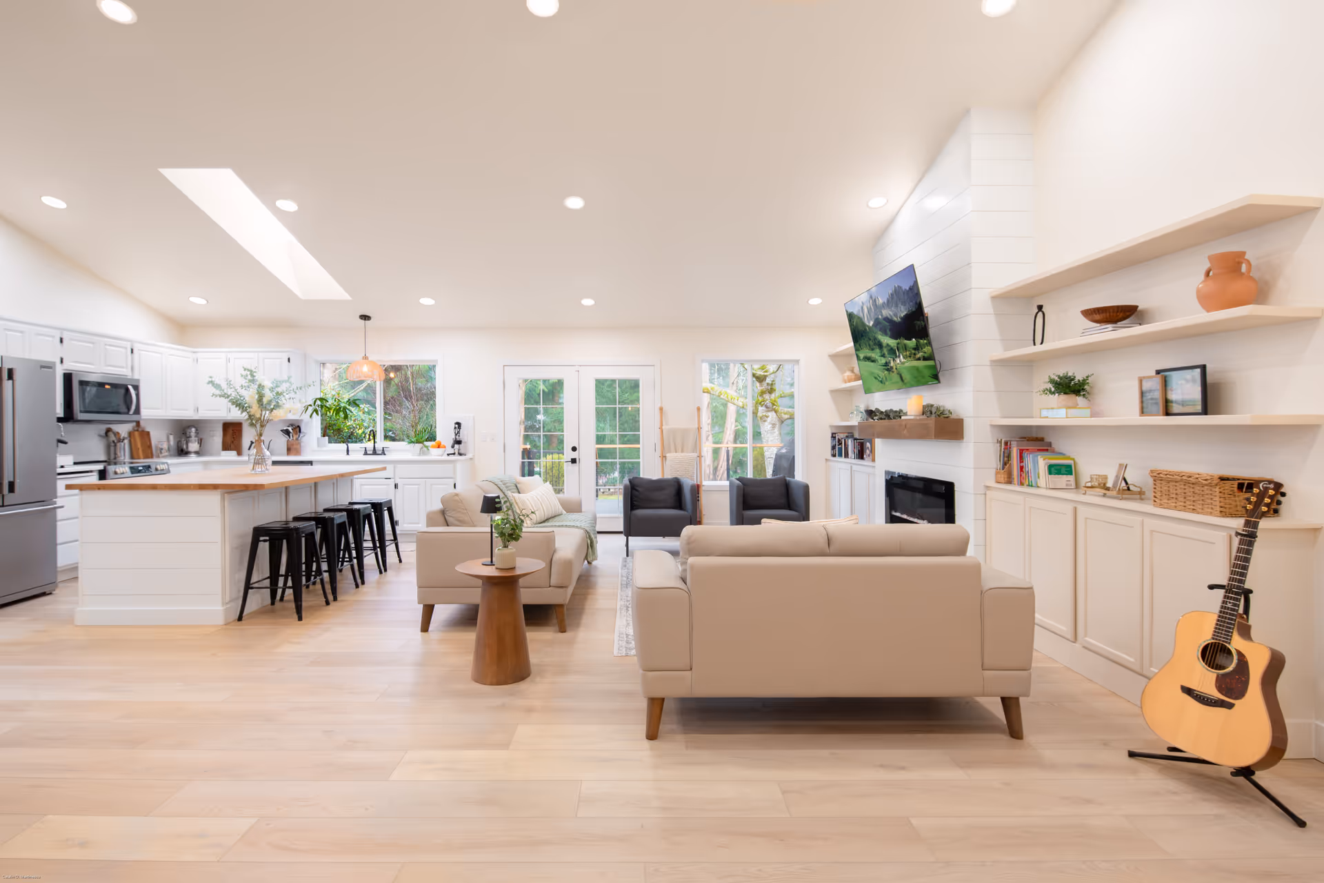 Bright open-concept senior living space with a white kitchen, bar stools, and lounge seating.