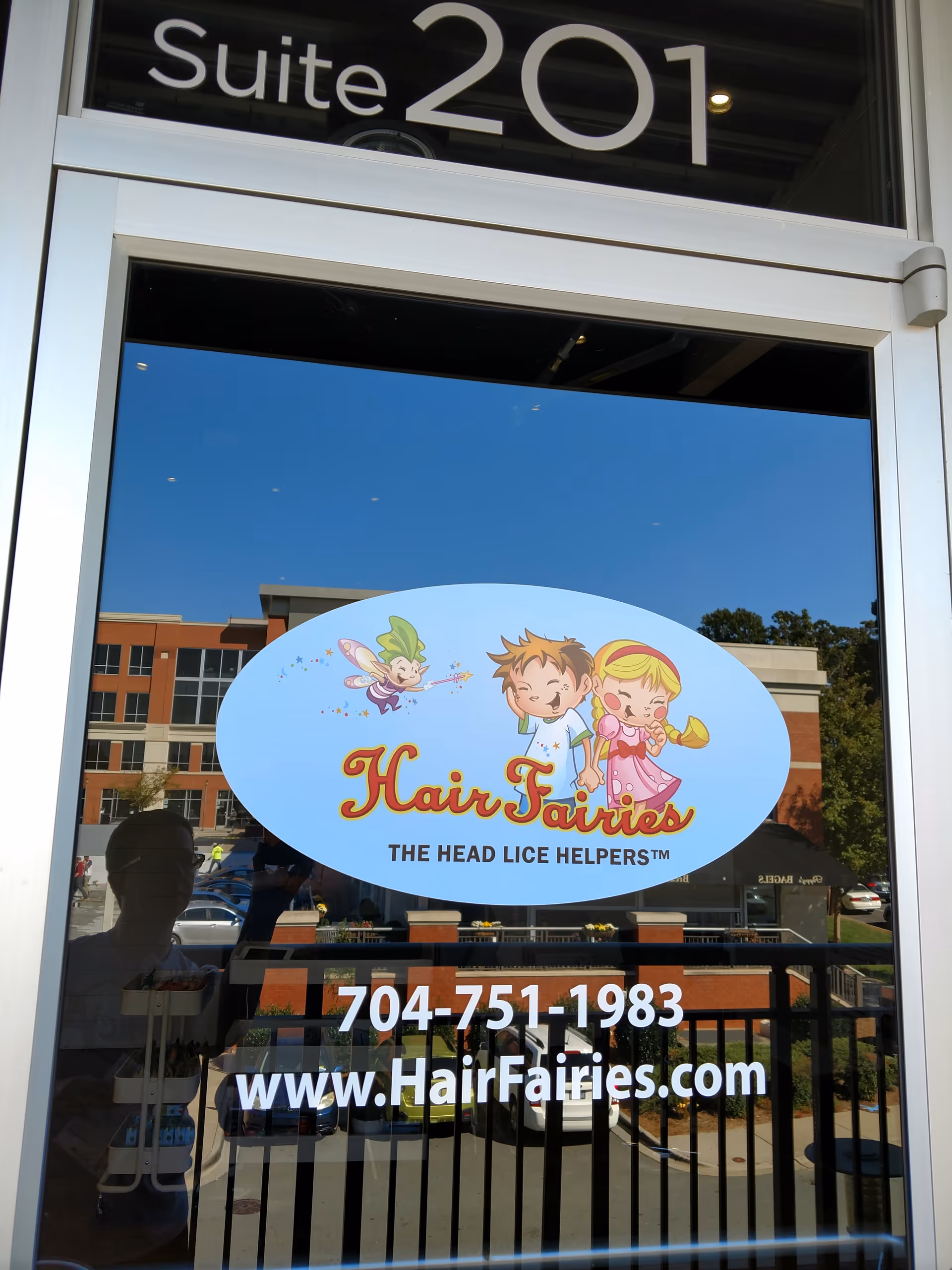 Glass door entrance displaying Hair Fairies logo and Suite 201 sign above