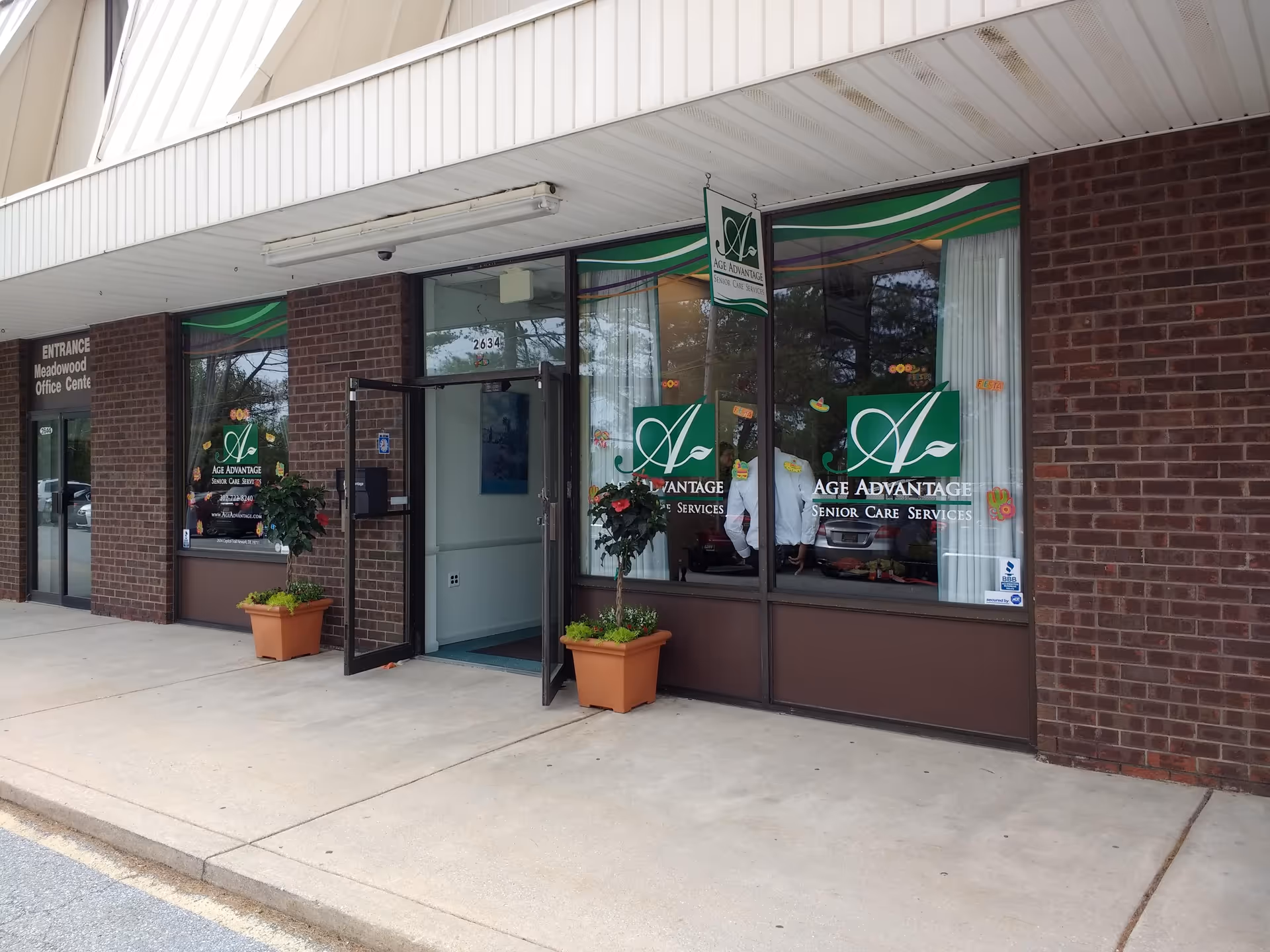 Age Advantage senior care storefront with glass windows and potted plants.