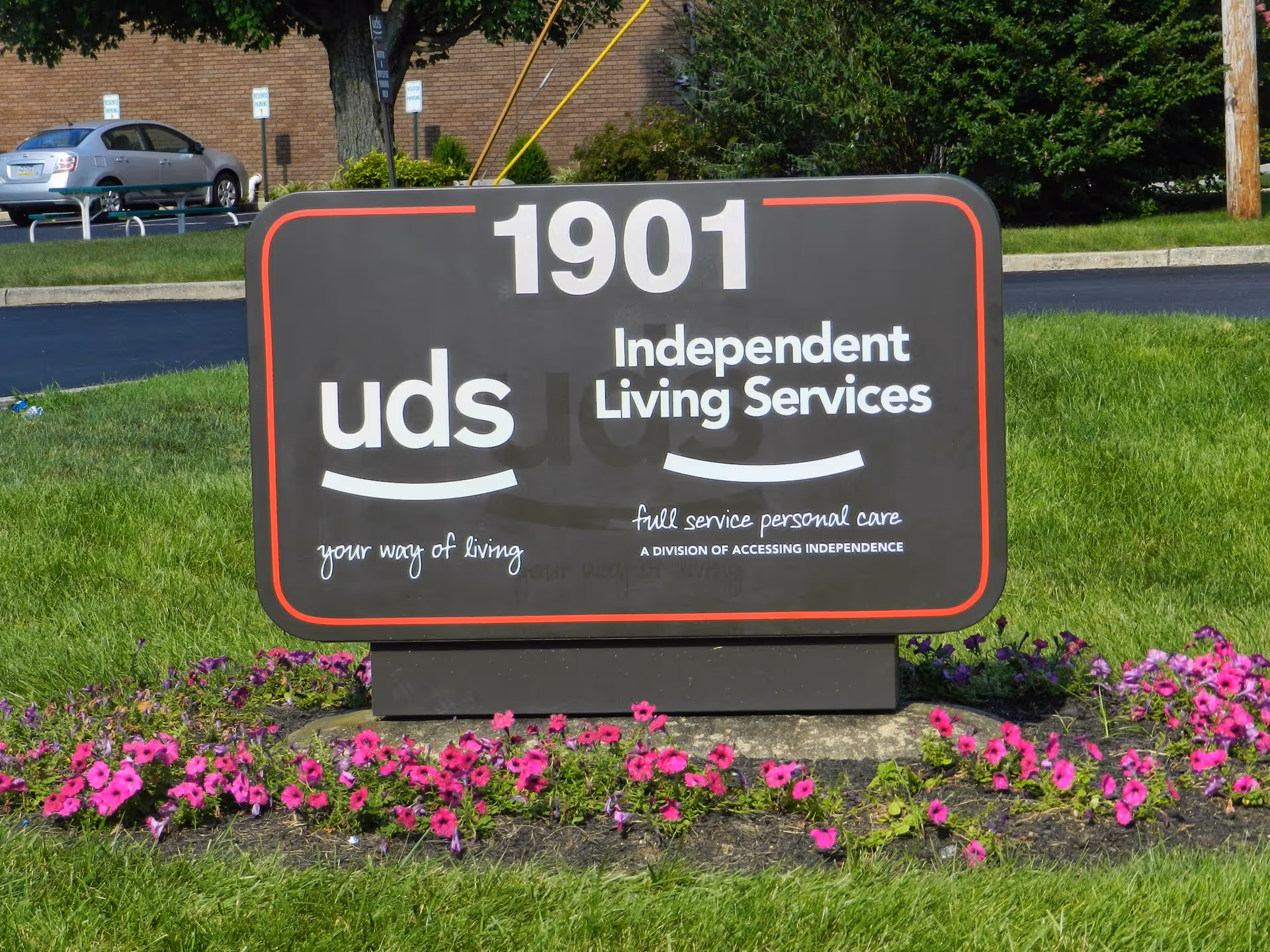 A large black sign for United Disabilities Services with 'Independent Living Services' on a grassy lawn.