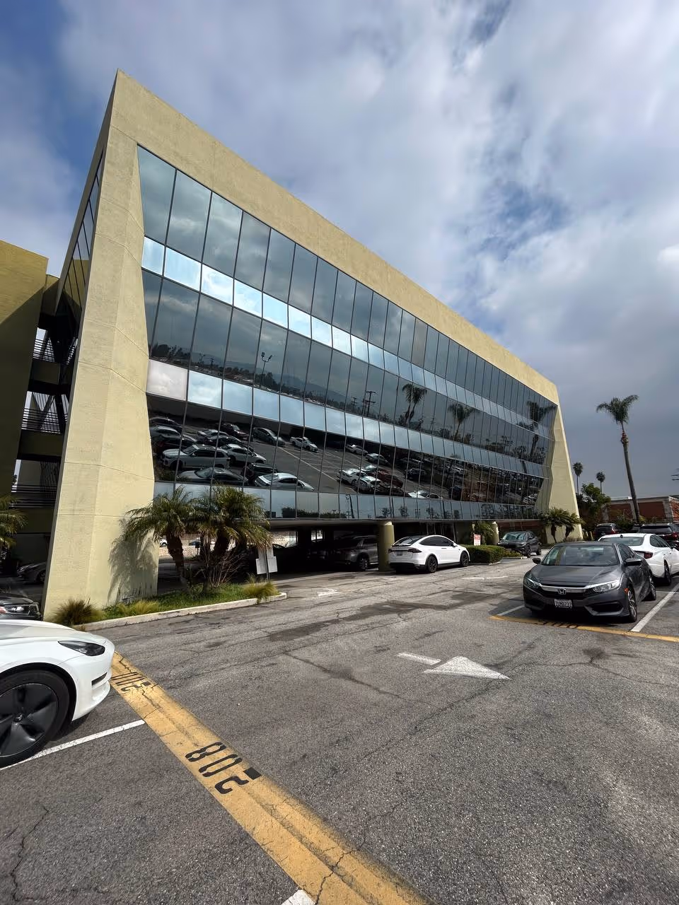 Glass-front building with reflective windows and a parking lot.
