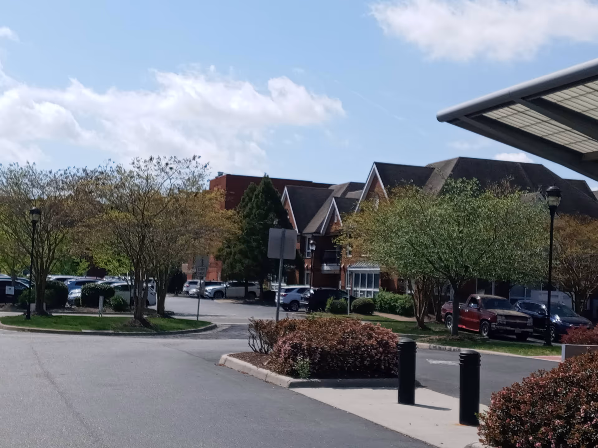 Exterior view of a building with a parking lot, trees, and a covered entry.