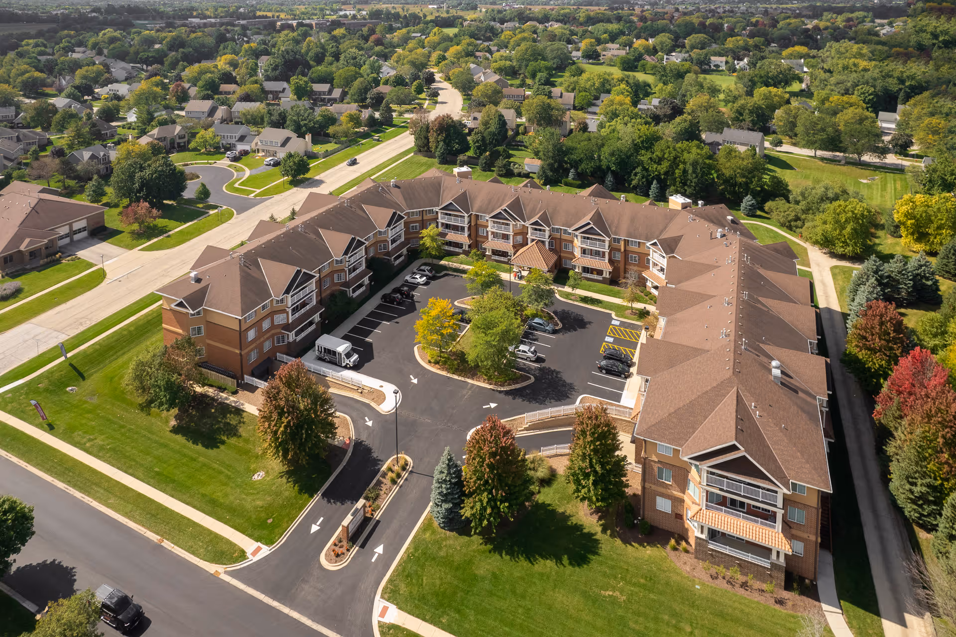 Aerial view of a senior living campus with brown-brick buildings and parking.