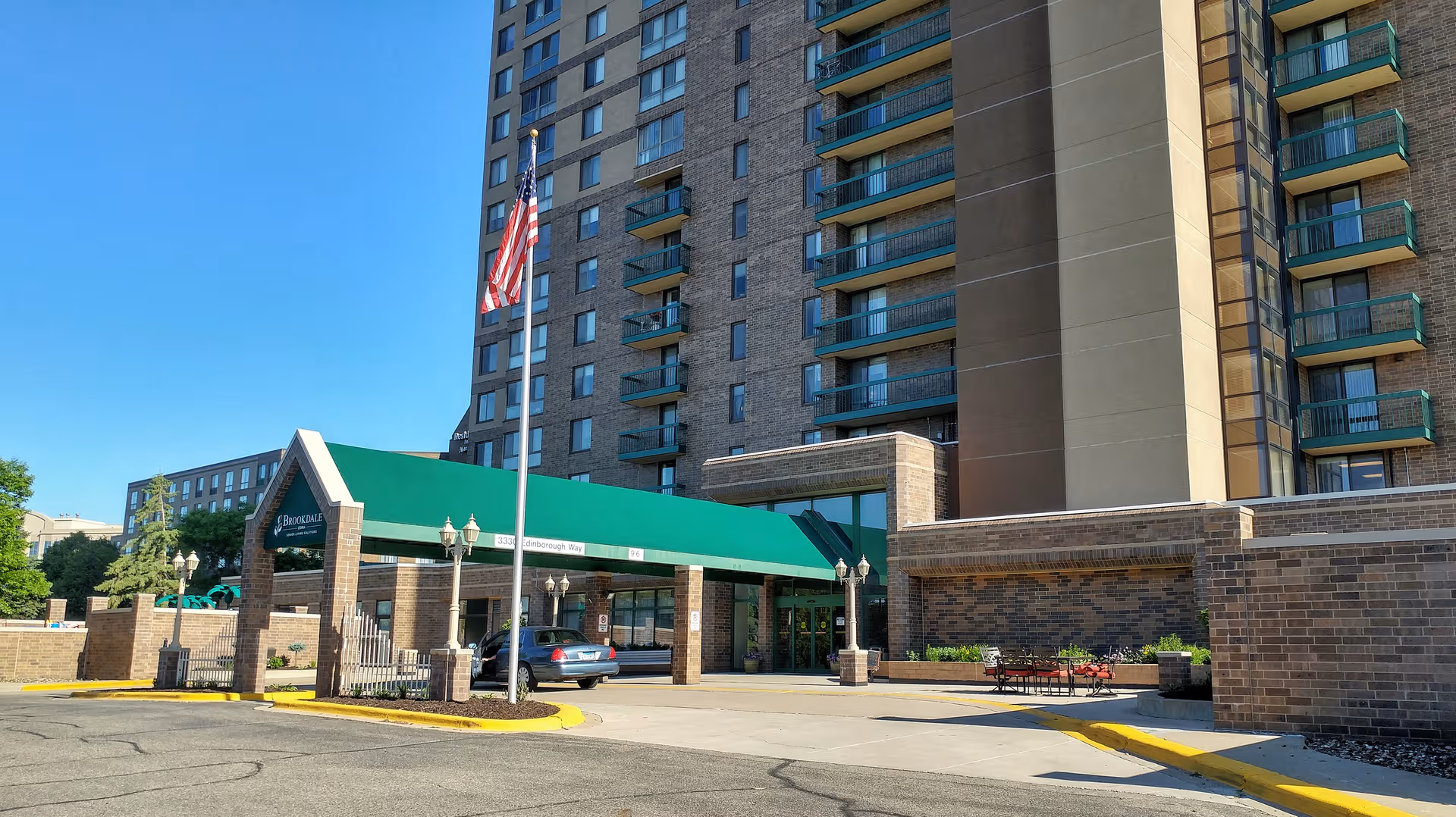 Brookdale Edina senior living building with green canopy entrance and American flag