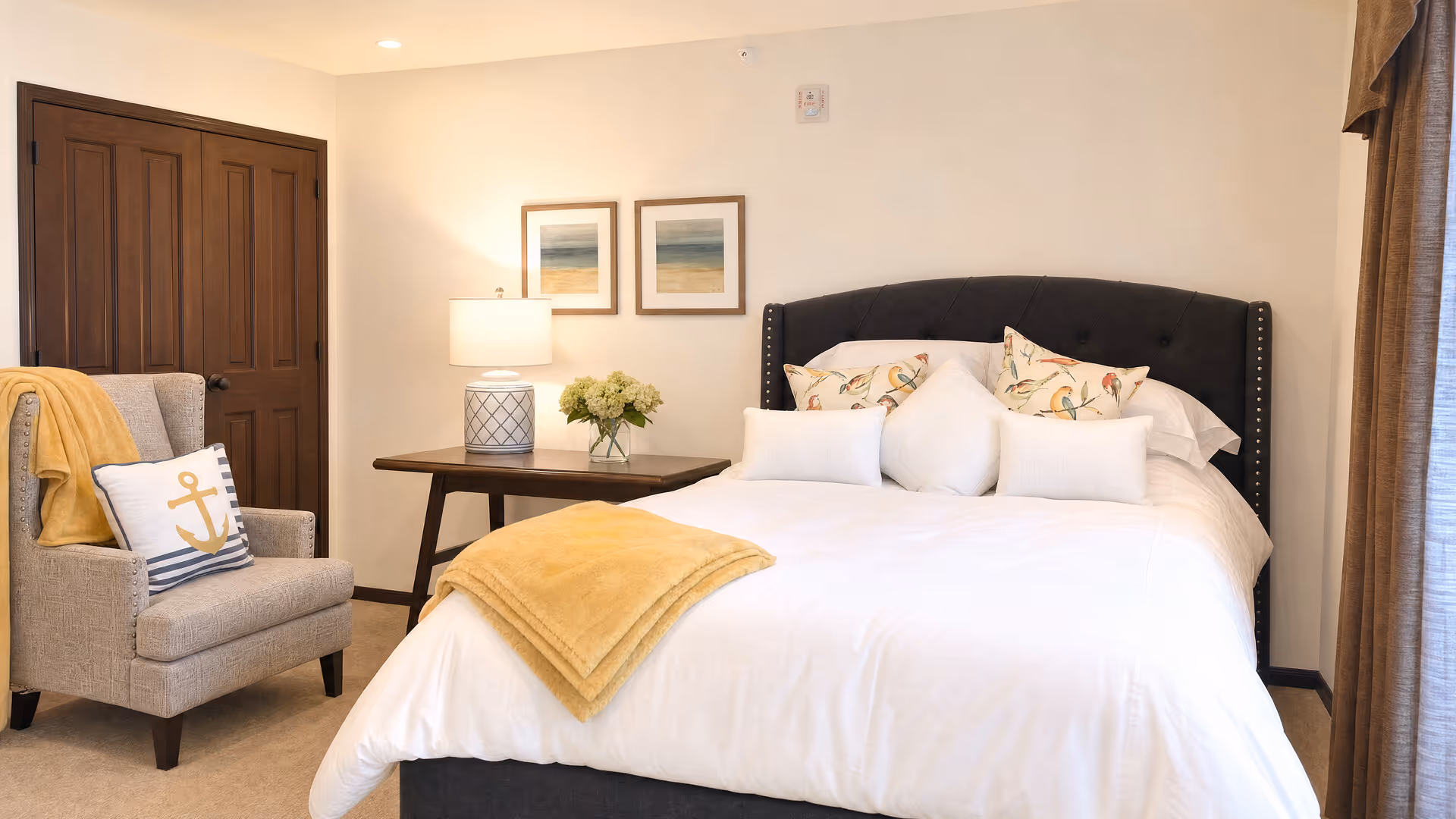 Cozy bedroom featuring a large bed, nightstand with lamp, and an armchair.