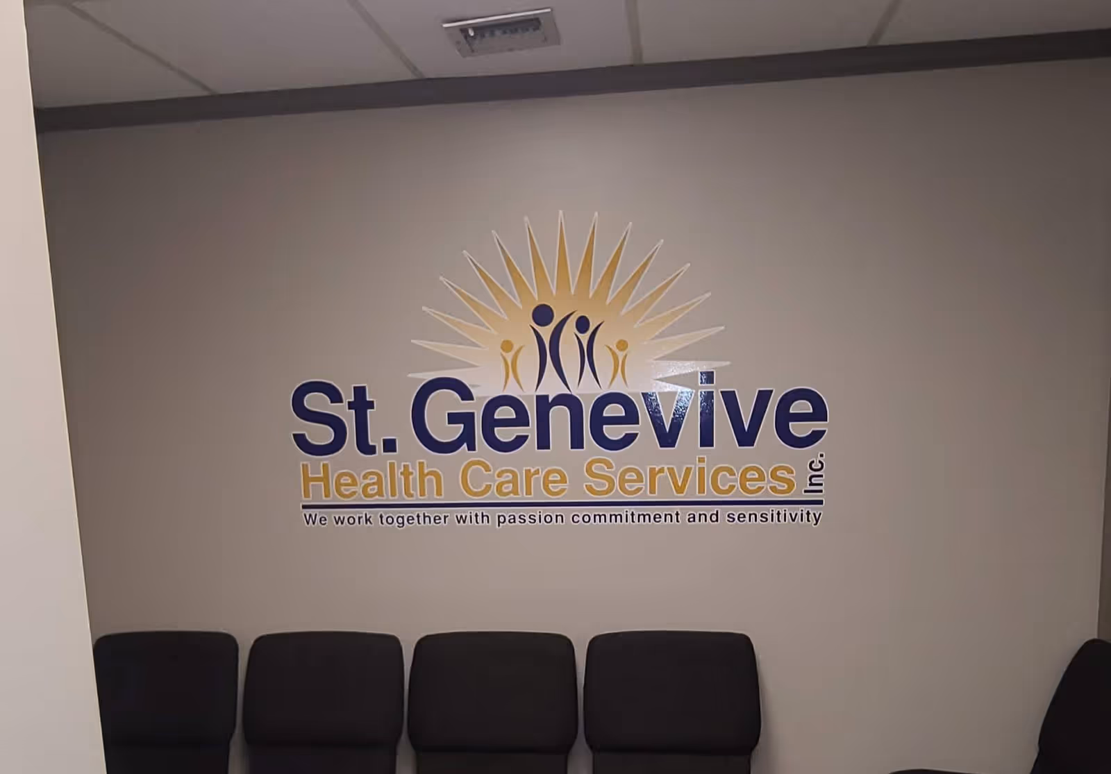 Interior wall featuring St. Genevive Health Care Services logo and chairs.