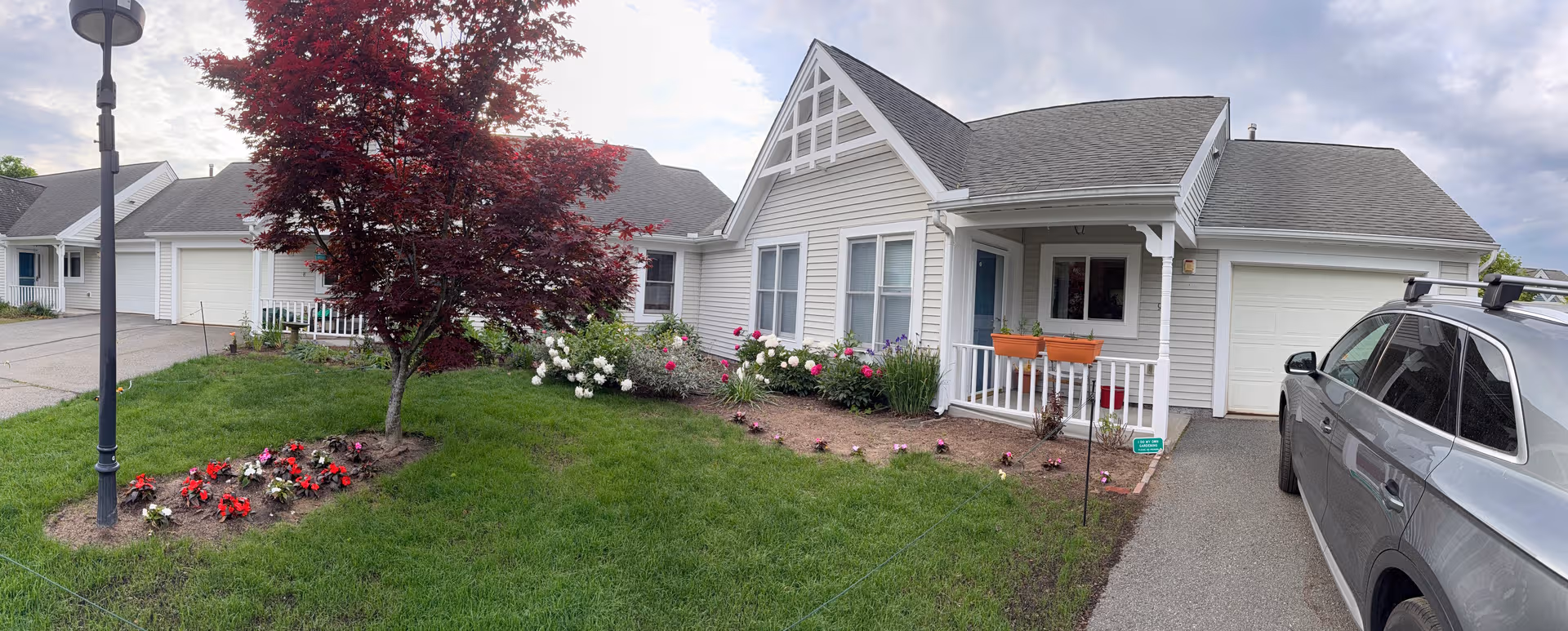 Front exterior of Lathrop Retirement Community with lawn, flowers, and parked car.