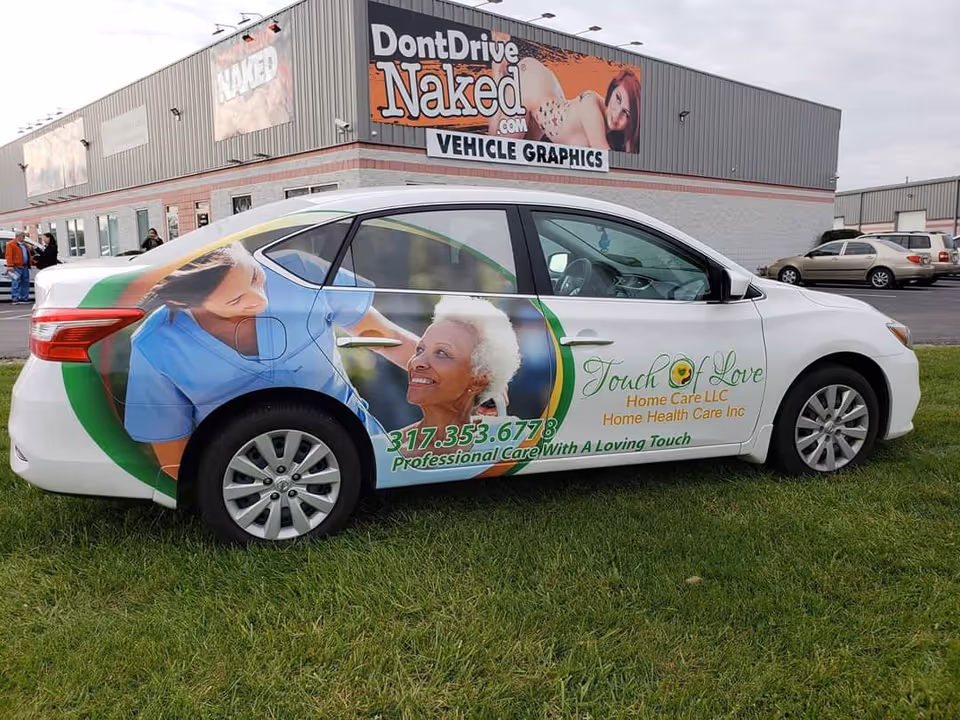 Car with colorful Touch of Love Home Care wrap parked beside a building.