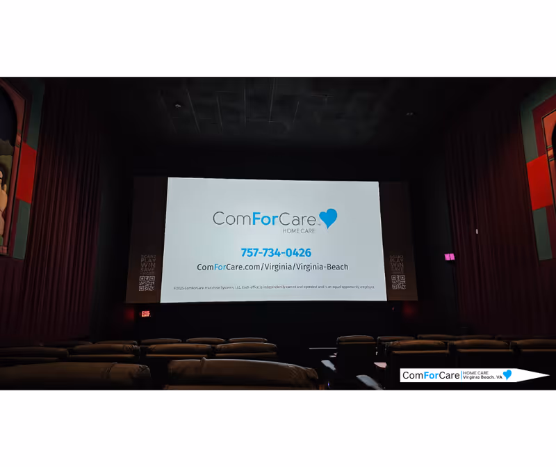 Dark theater room with a large screen displaying ComForCare logo and empty seats
