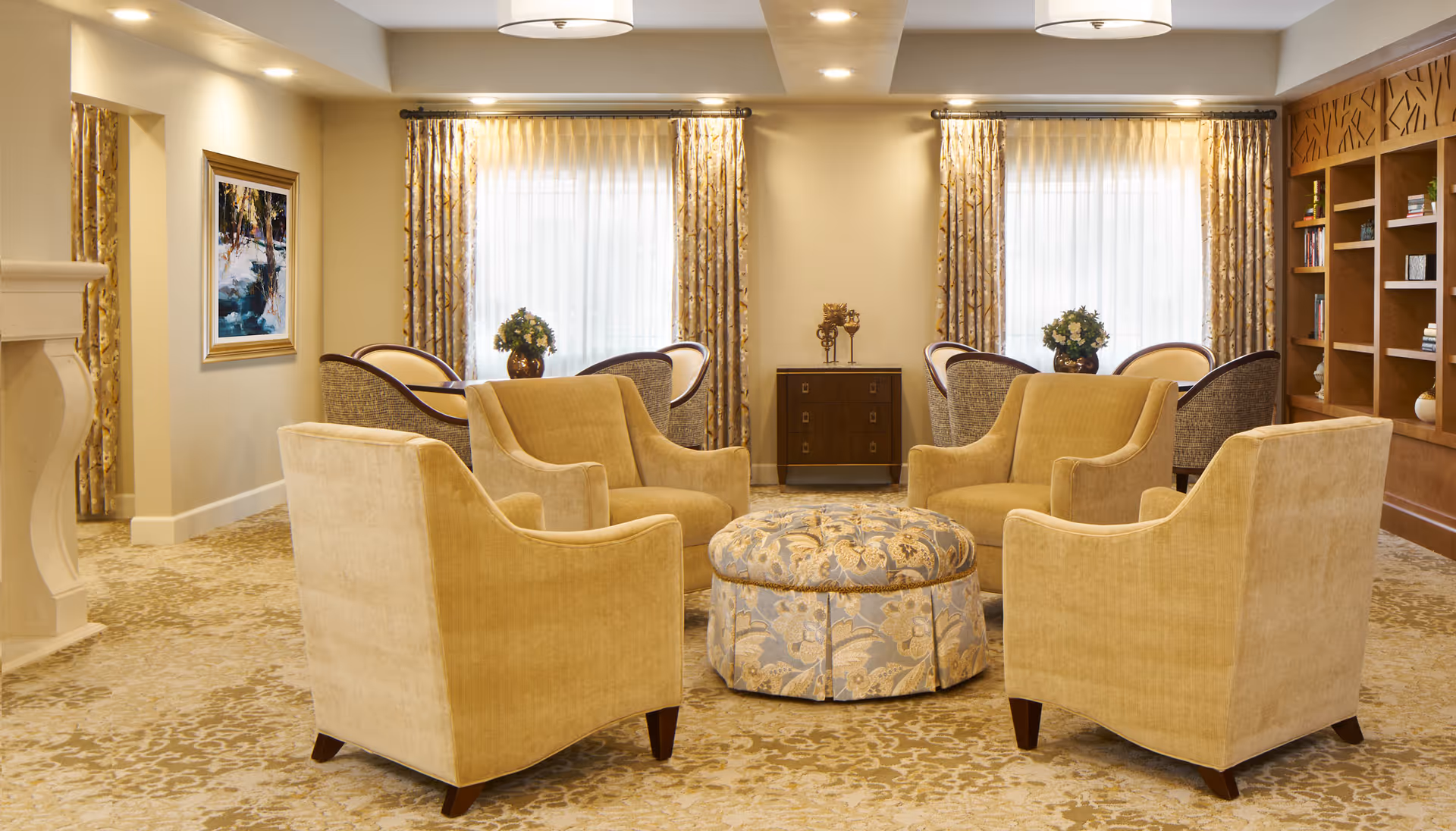 Cozy beige senior living lounge with circular ottoman and armchairs.