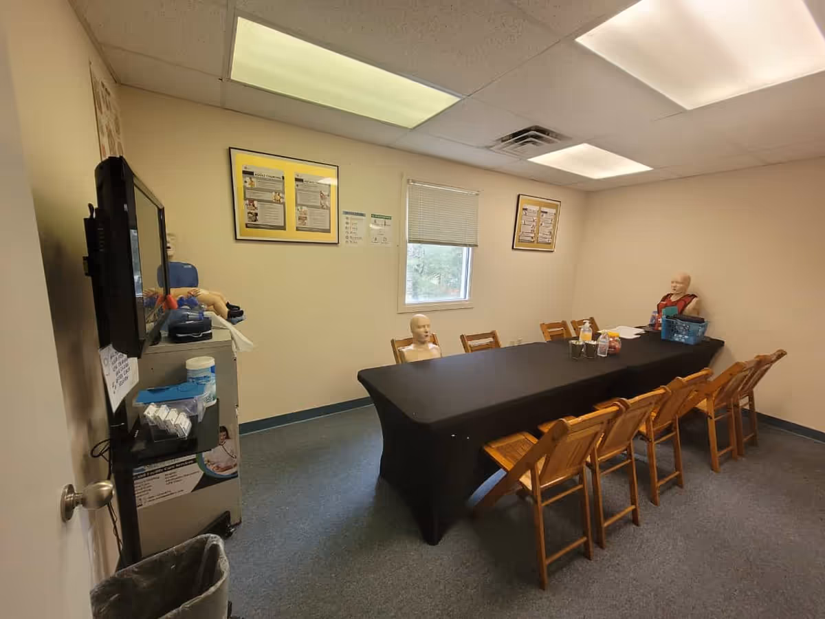 A training room with a long table and mannequins for HHA CPR training