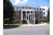 Brick Ivy Hall Nursing Home exterior with white columns and stairs leading to the front entrance.