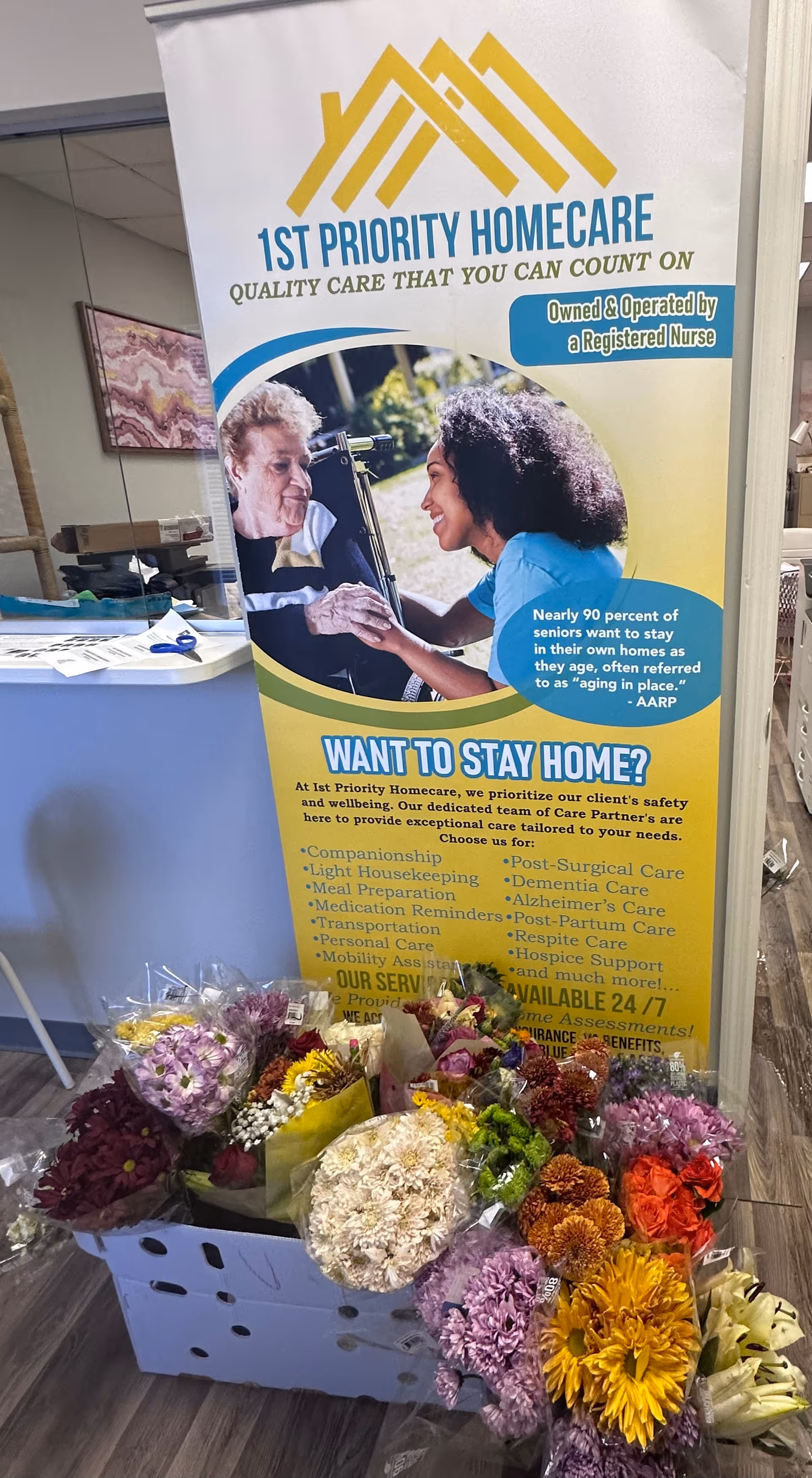 Indoor reception area features a 1st Priority Homecare banner and colorful flowers.