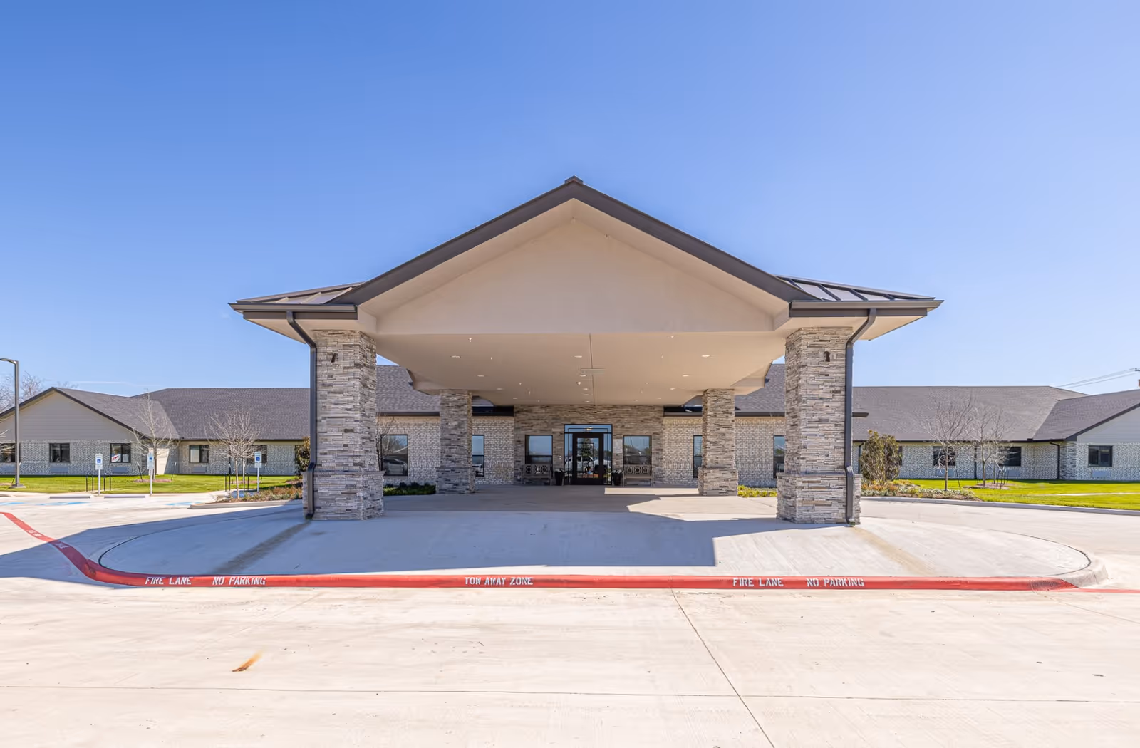 Exterior view of a modern senior living entrance with a covered drop-off area.
