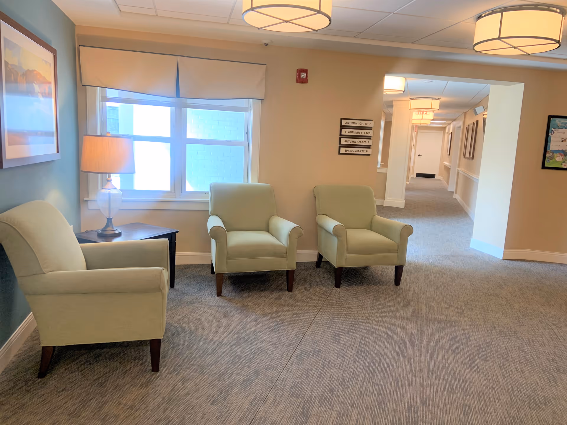 Comfortable mint-green chairs arranged in a cozy lounge with a window and lamp.