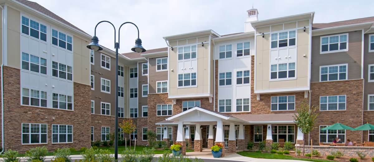 Exterior view of The Greens at Hammonds Lane, a multi-story senior living building with brick facade.