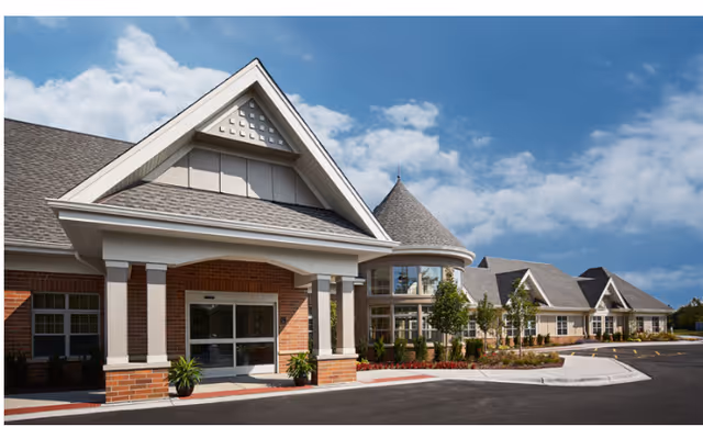Exterior view of Alden Courts of Shorewood, a brick senior living facility with entryway and parking.