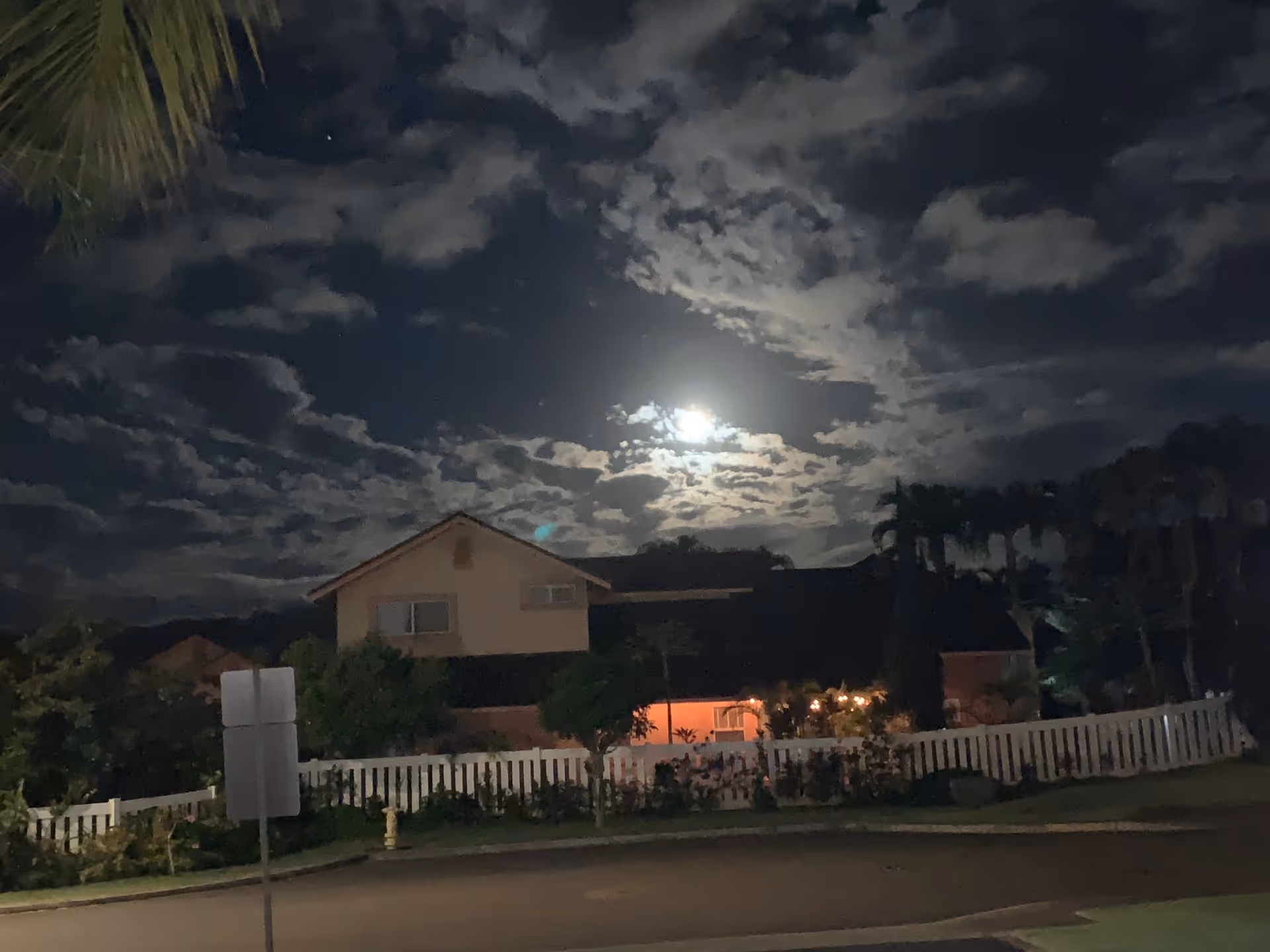 Night view of a facility's front exterior with a white picket fence under a moonlit sky.