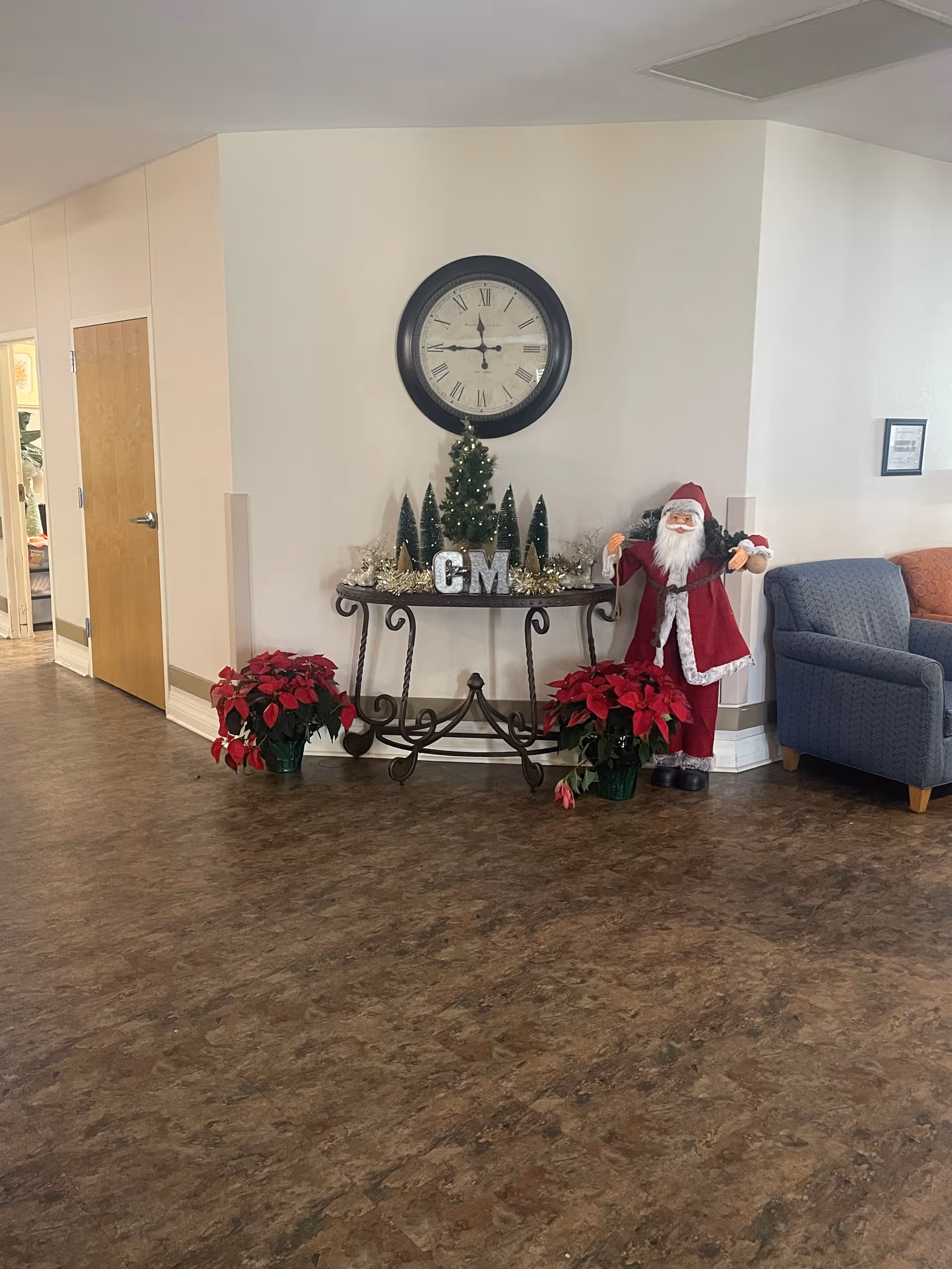 Lobby area adorned with Christmas decorations, a large clock, poinsettias, and a Santa figure.