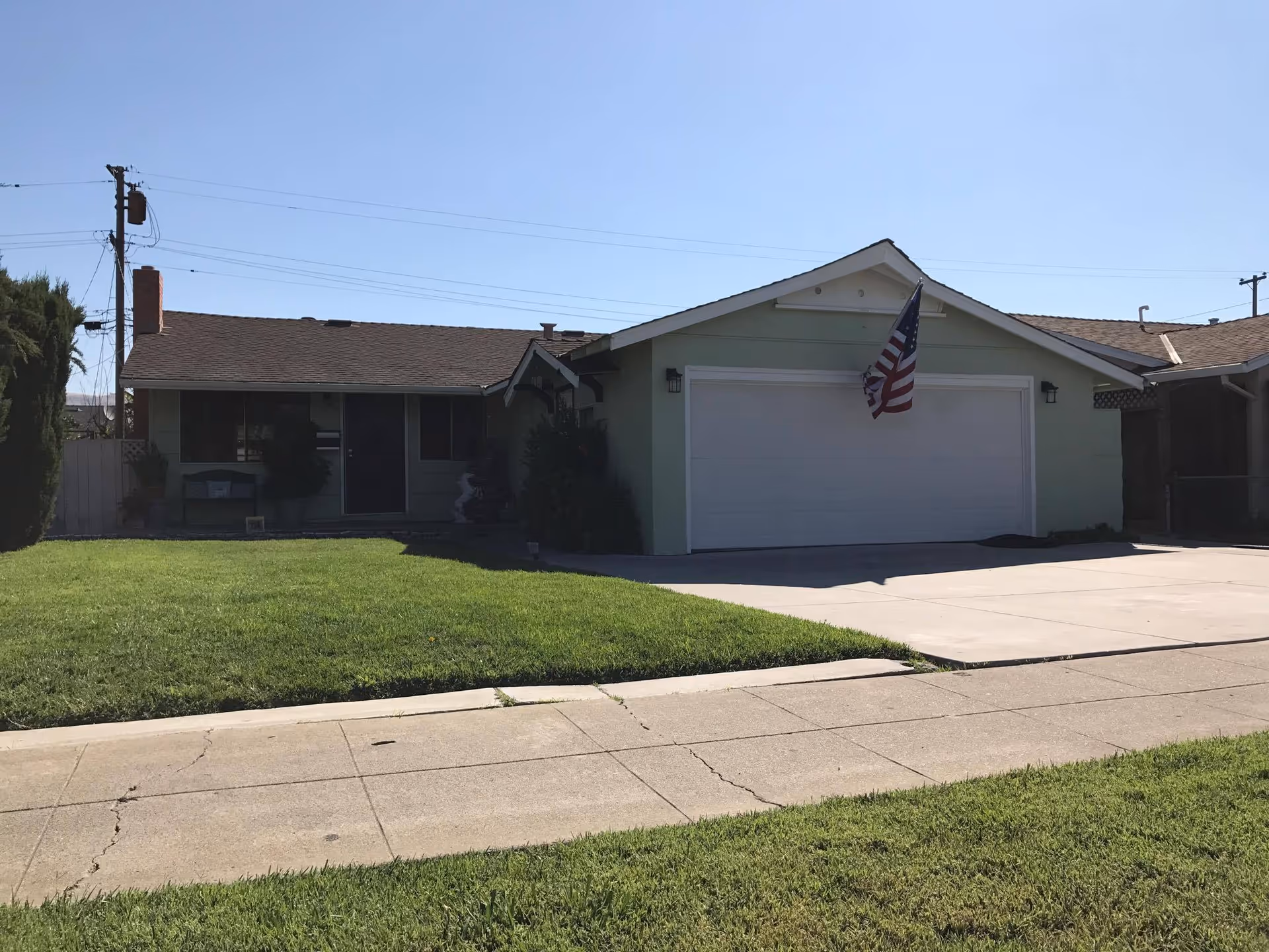 Front view of a single-story residence with a two-car garage and American flag.