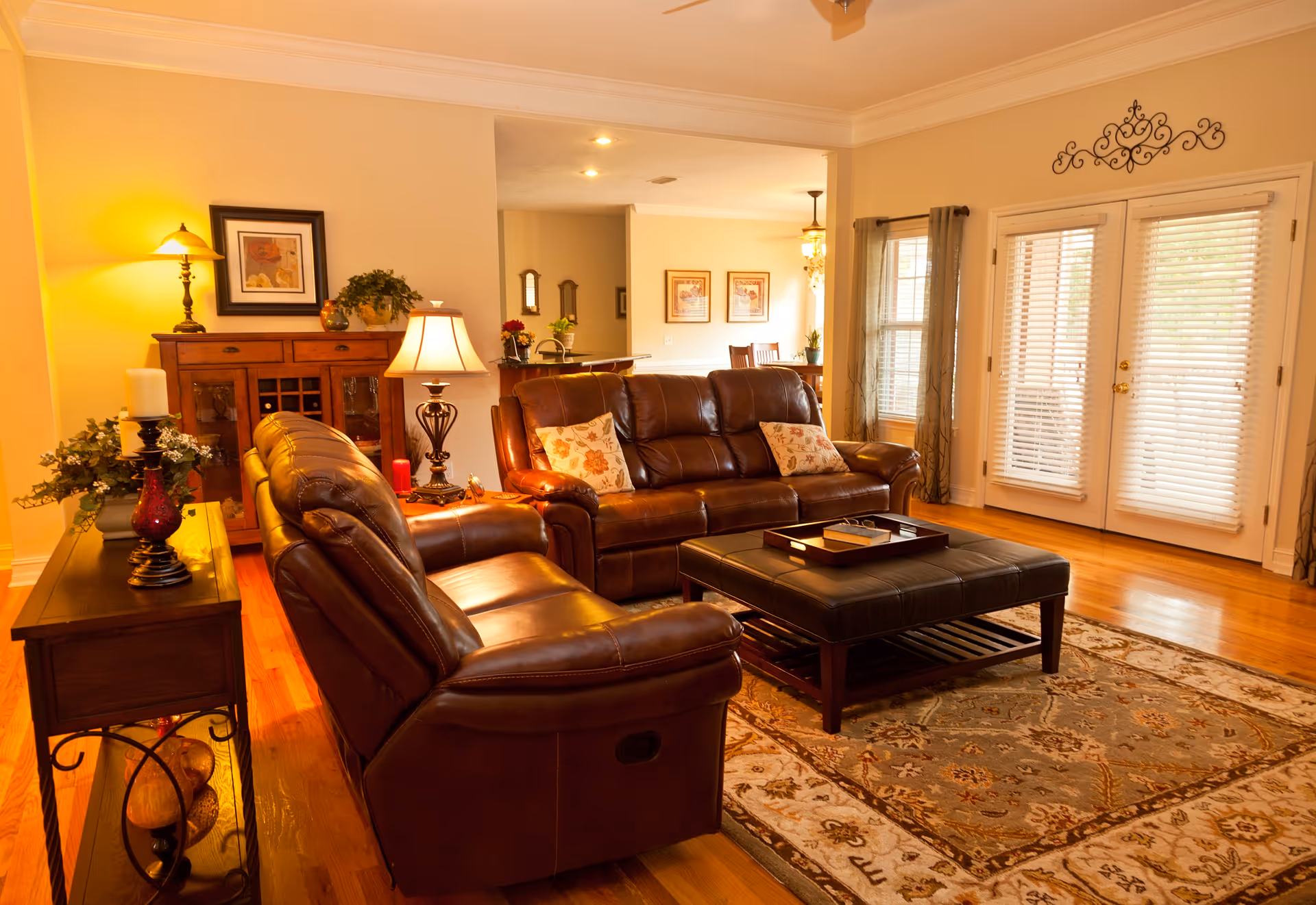 Cozy living room with leather sofas, coffee table, decorative rug, and glass French doors.