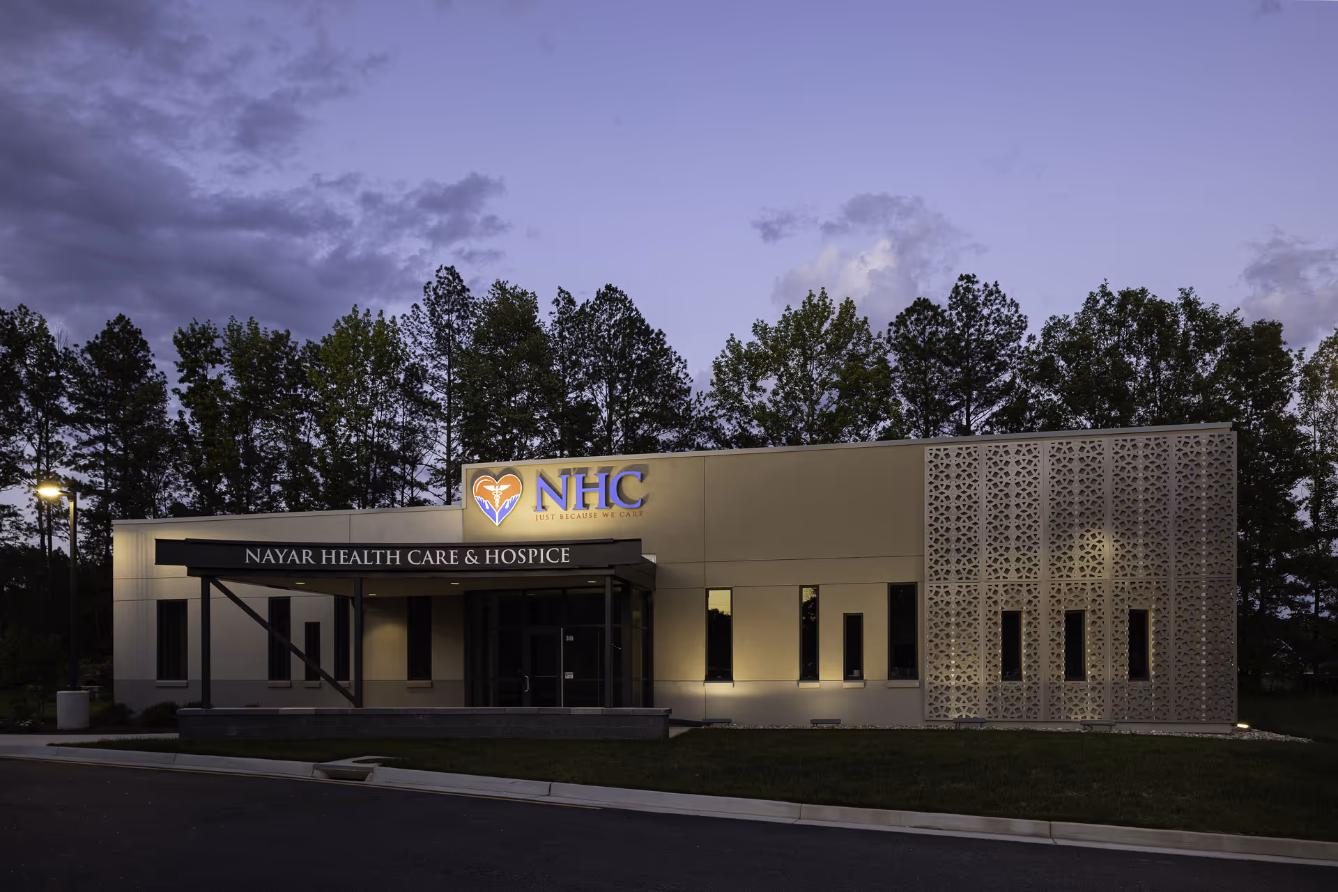 Exterior view of Nayar Health Care & Hospice building with illuminated sign at dusk.