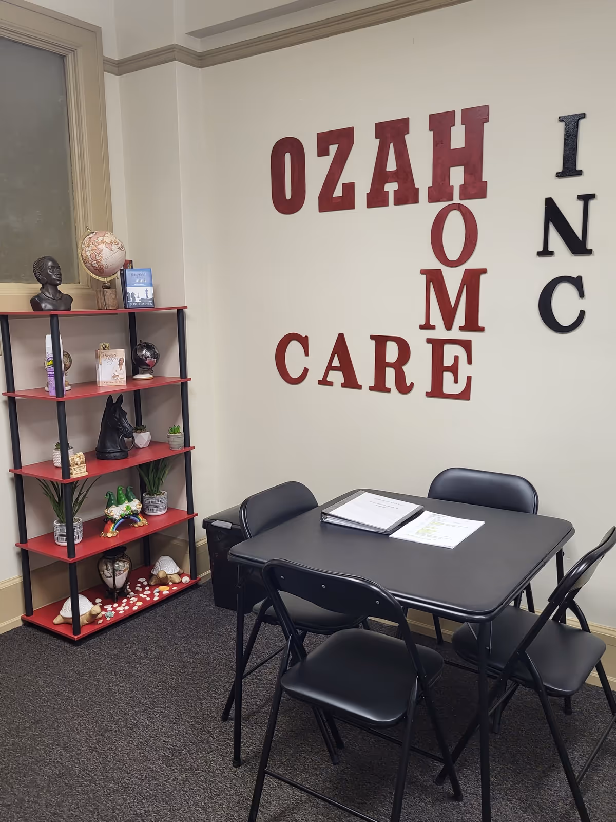 Interior room with a black table, folding chairs, and OZAH CARE wall letters.