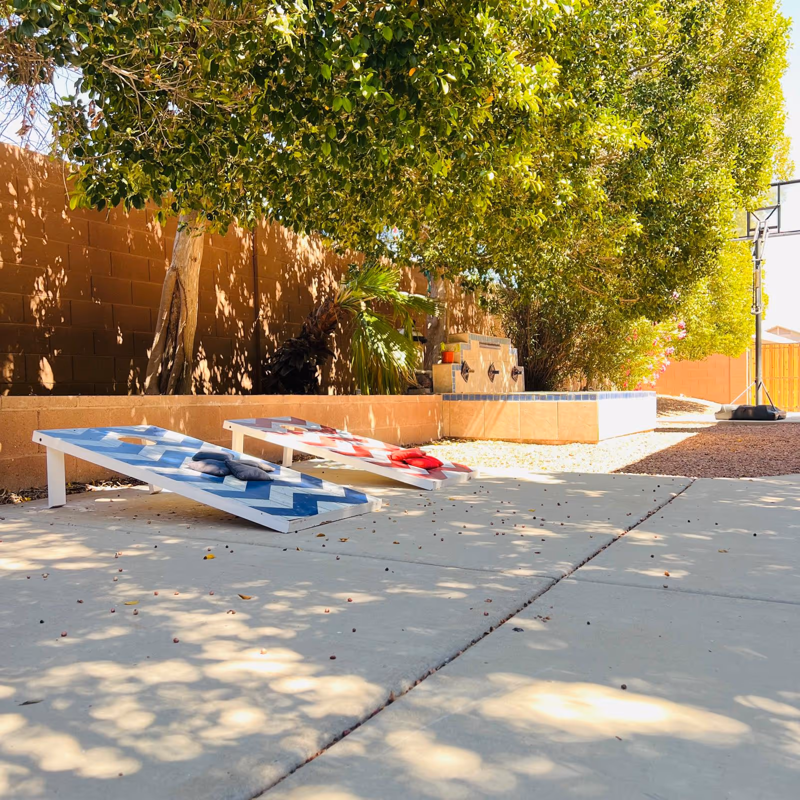 Outdoor courtyard with two cornhole boards and seating area beside a brick wall.