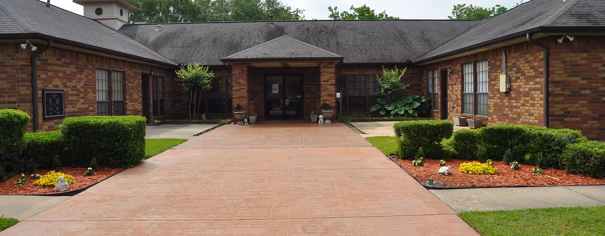 Exterior view of Independence Village building front with brick walls, walkway, and shrubs.